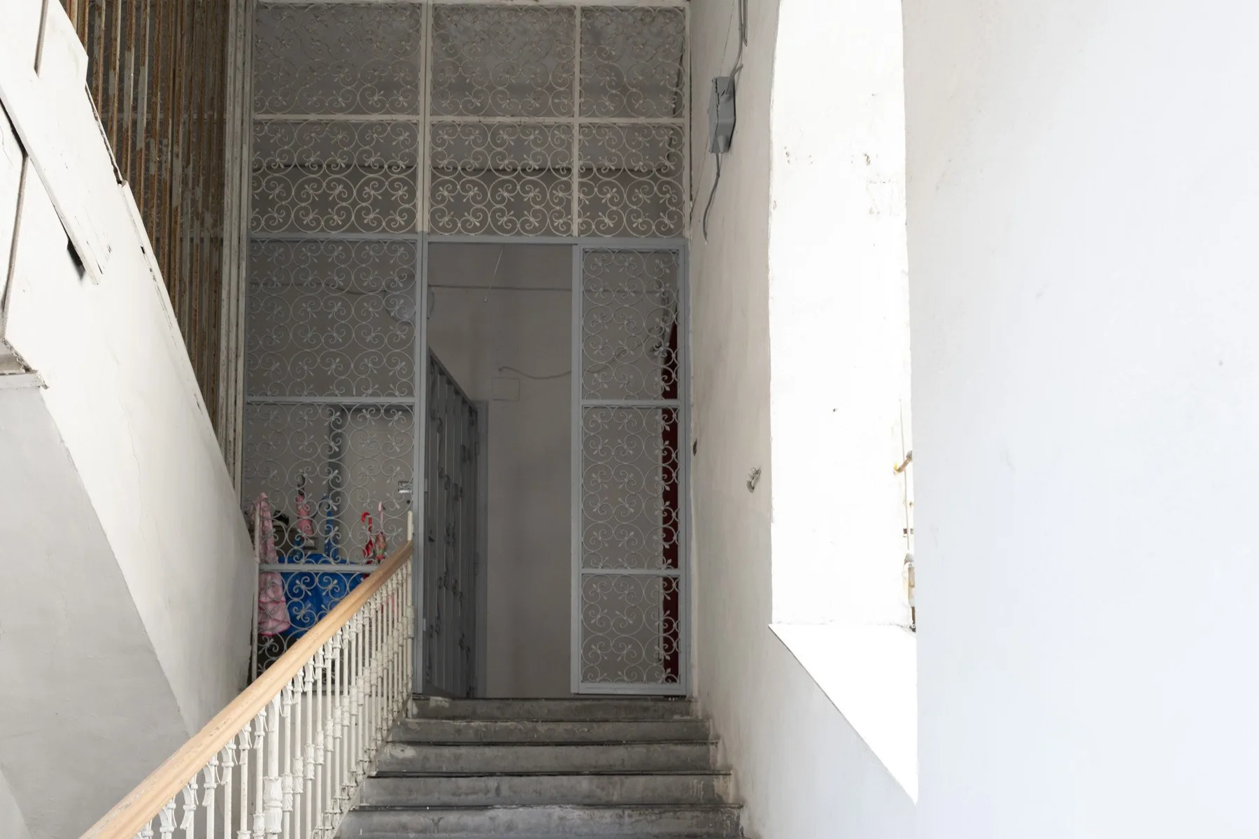 An interior staircase leads to a doorway beneath a decorative metal screen.