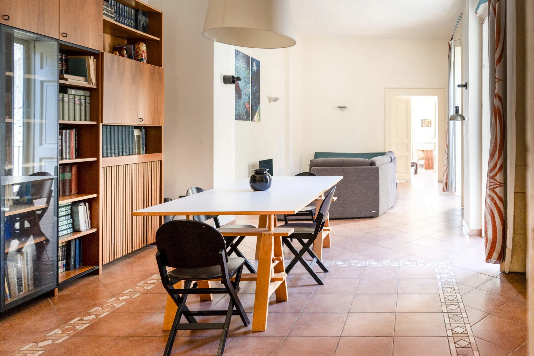 A dining area with a long table, chairs, and built-in bookshelves.