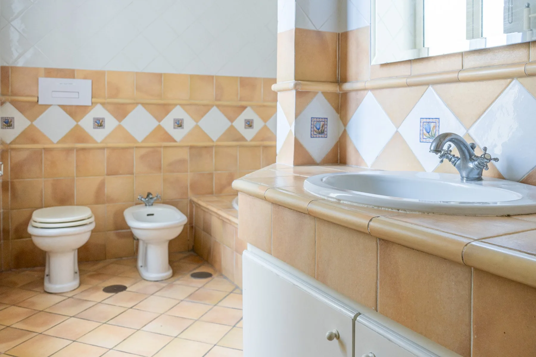 A tiled bathroom with a sink, toilet, and bidet.