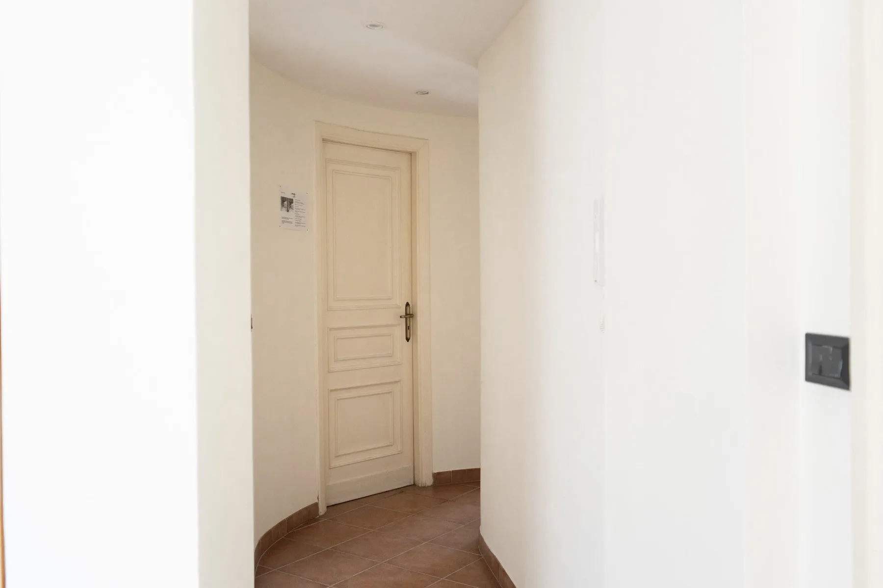 A narrow hallway with a closed paneled door at the end.