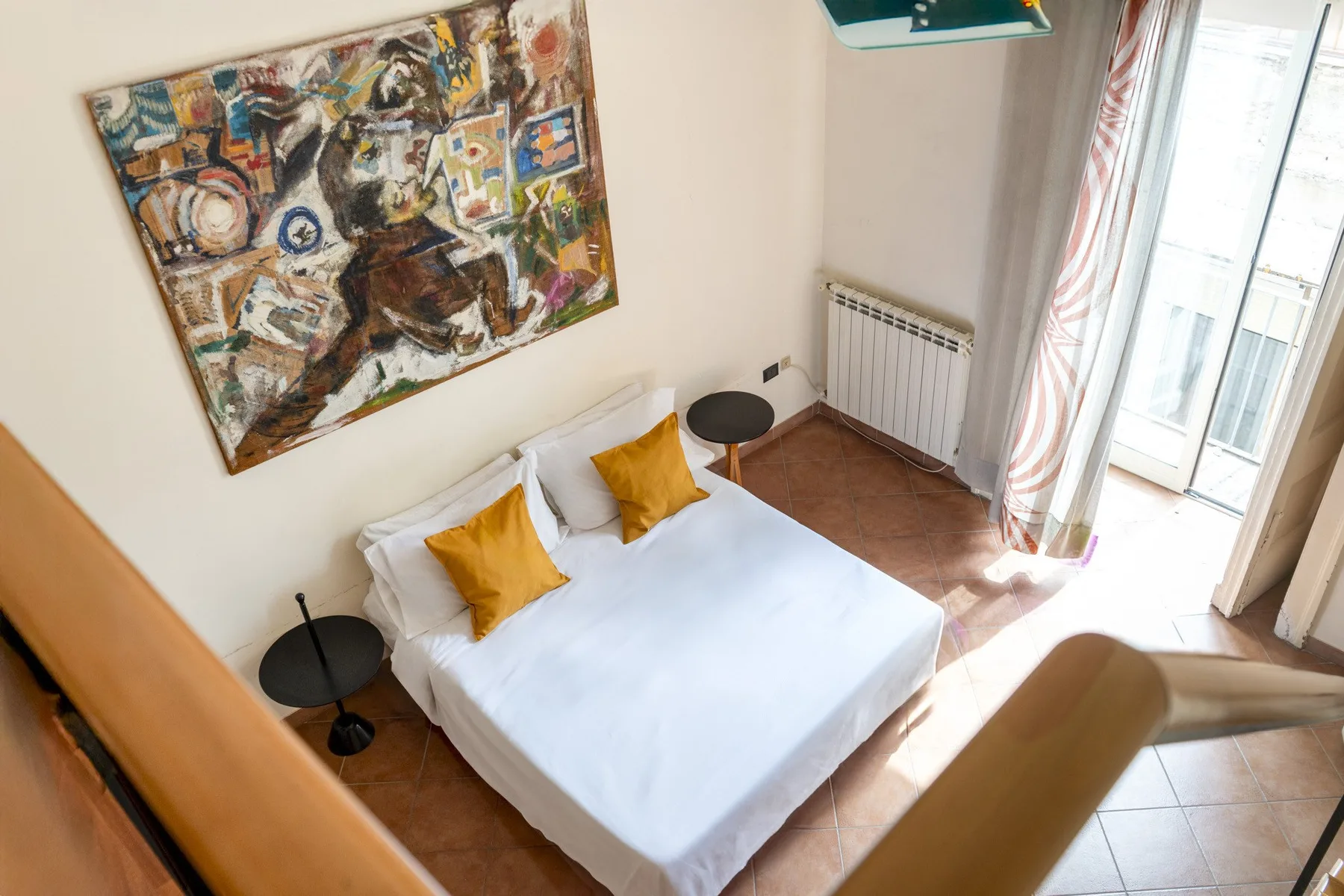 A bedroom with a bed, yellow pillows, and a large painting on the wall.