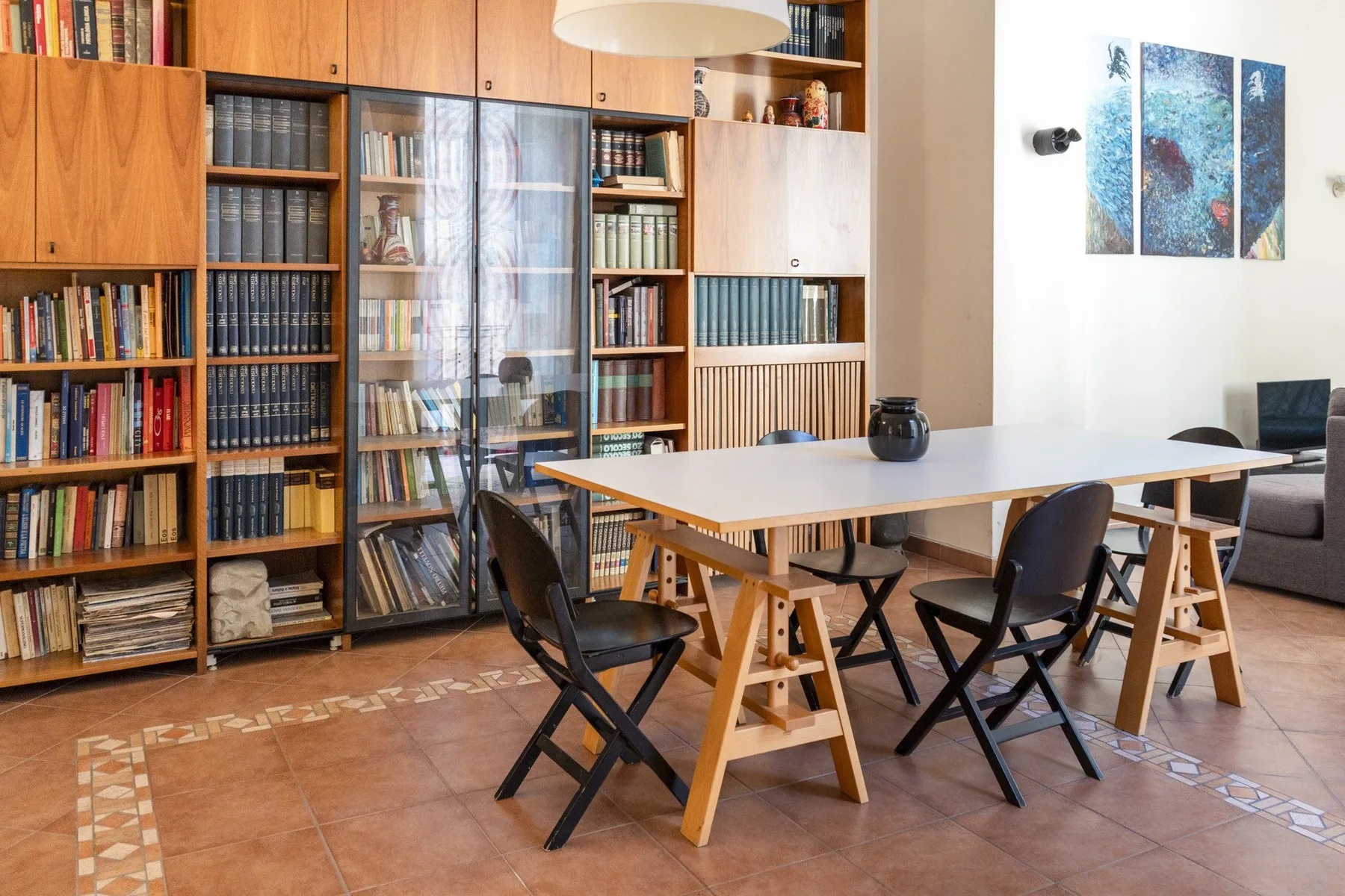 Una zona de comedor y lectura con una mesa larga y estanterías empotradas.