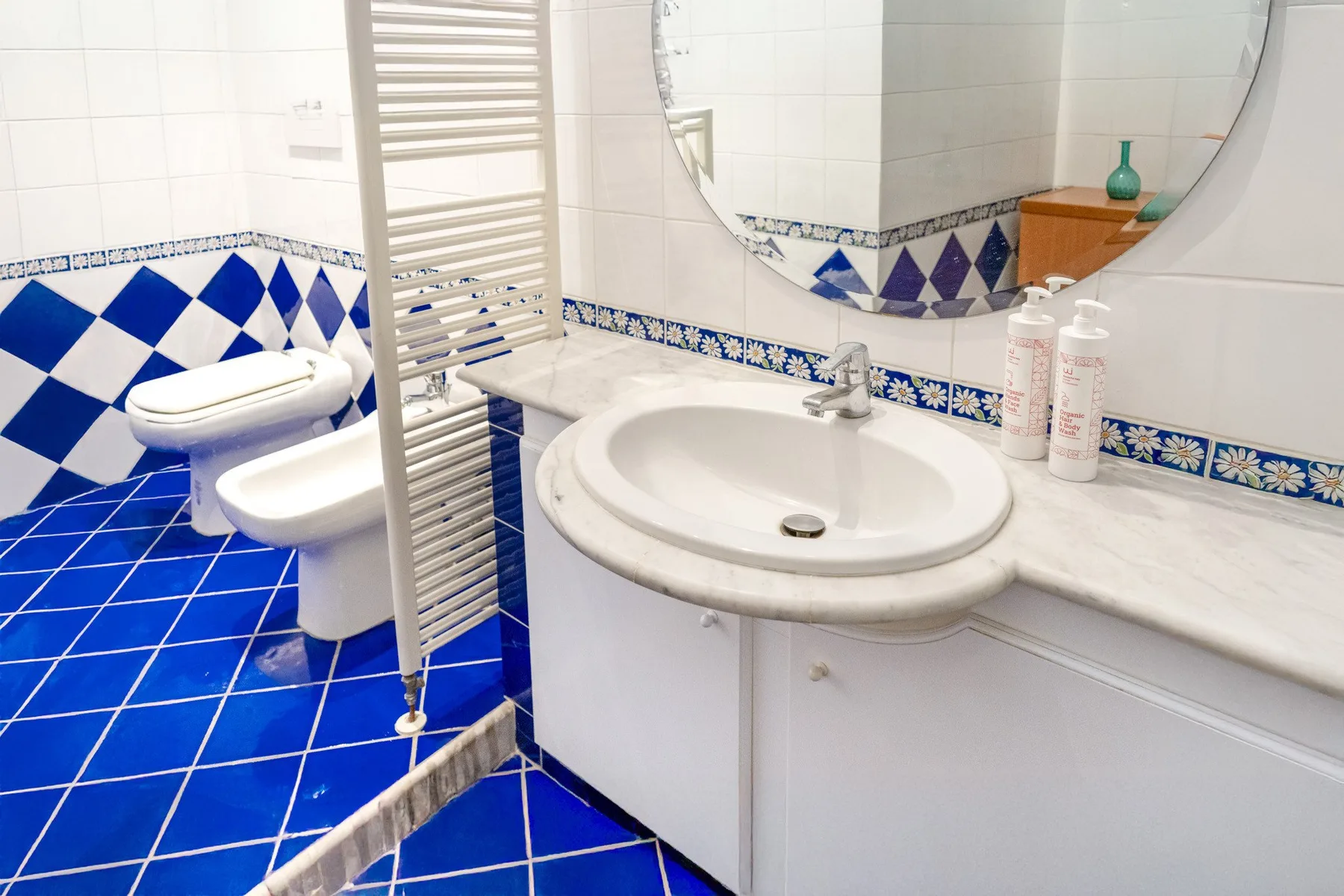 A tiled bathroom with a sink, mirror, and toilet.