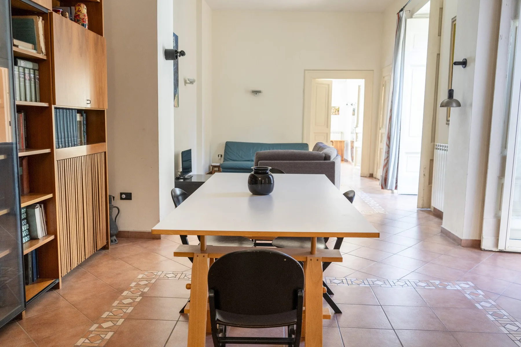 A dining area with a table and chairs beside a tall wooden bookcase.