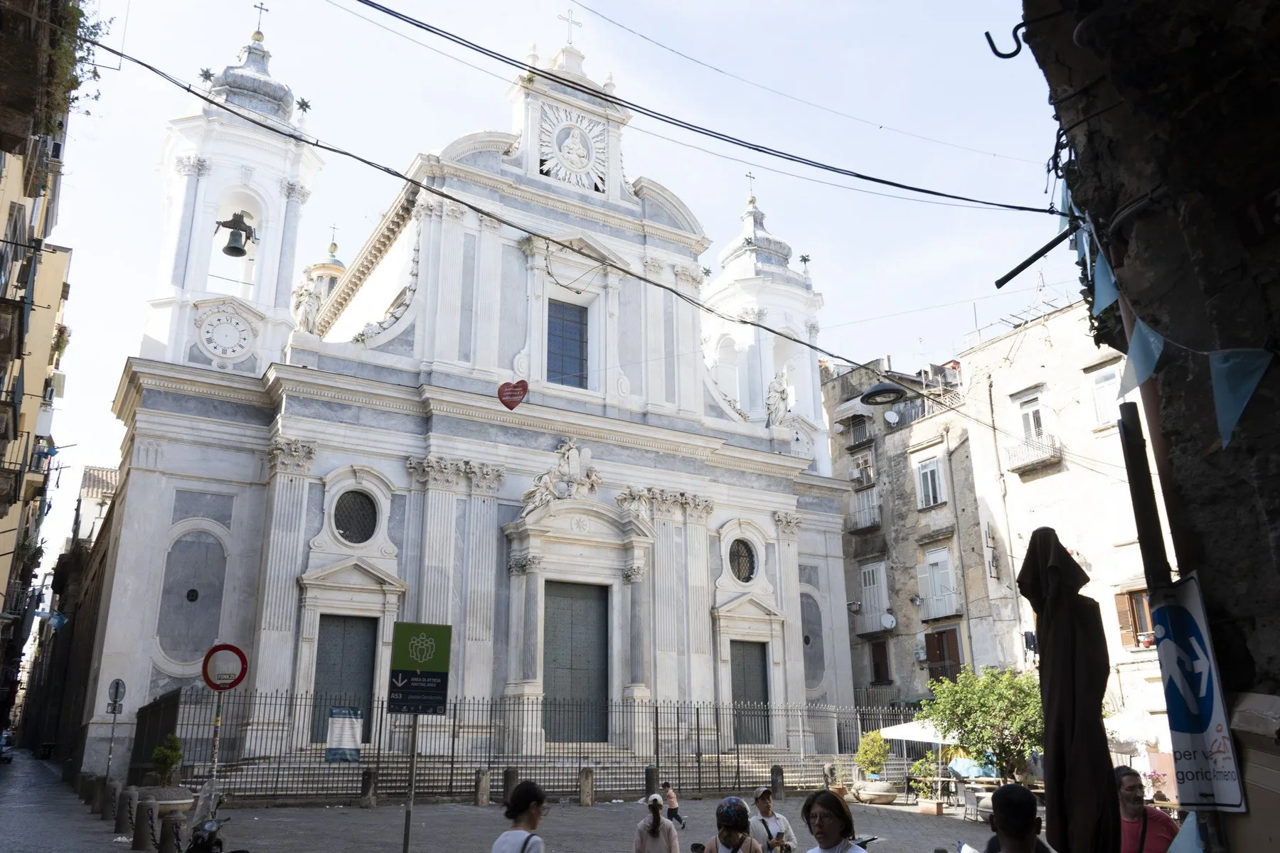 A large church facade with twin bell towers stands at the end of a narrow street.