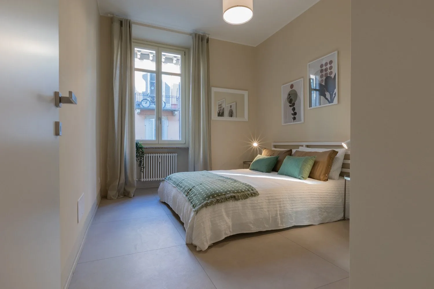 Un dormitorio con una cama bien tendida y una ventana con vistas a un balcón.
