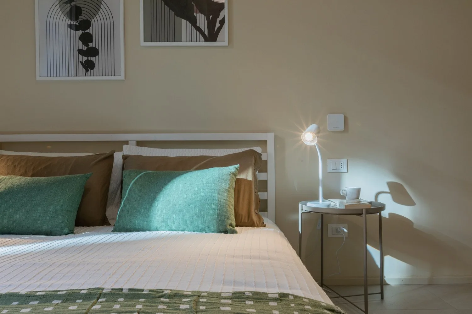 A bedroom with a neatly made bed and a small bedside table.