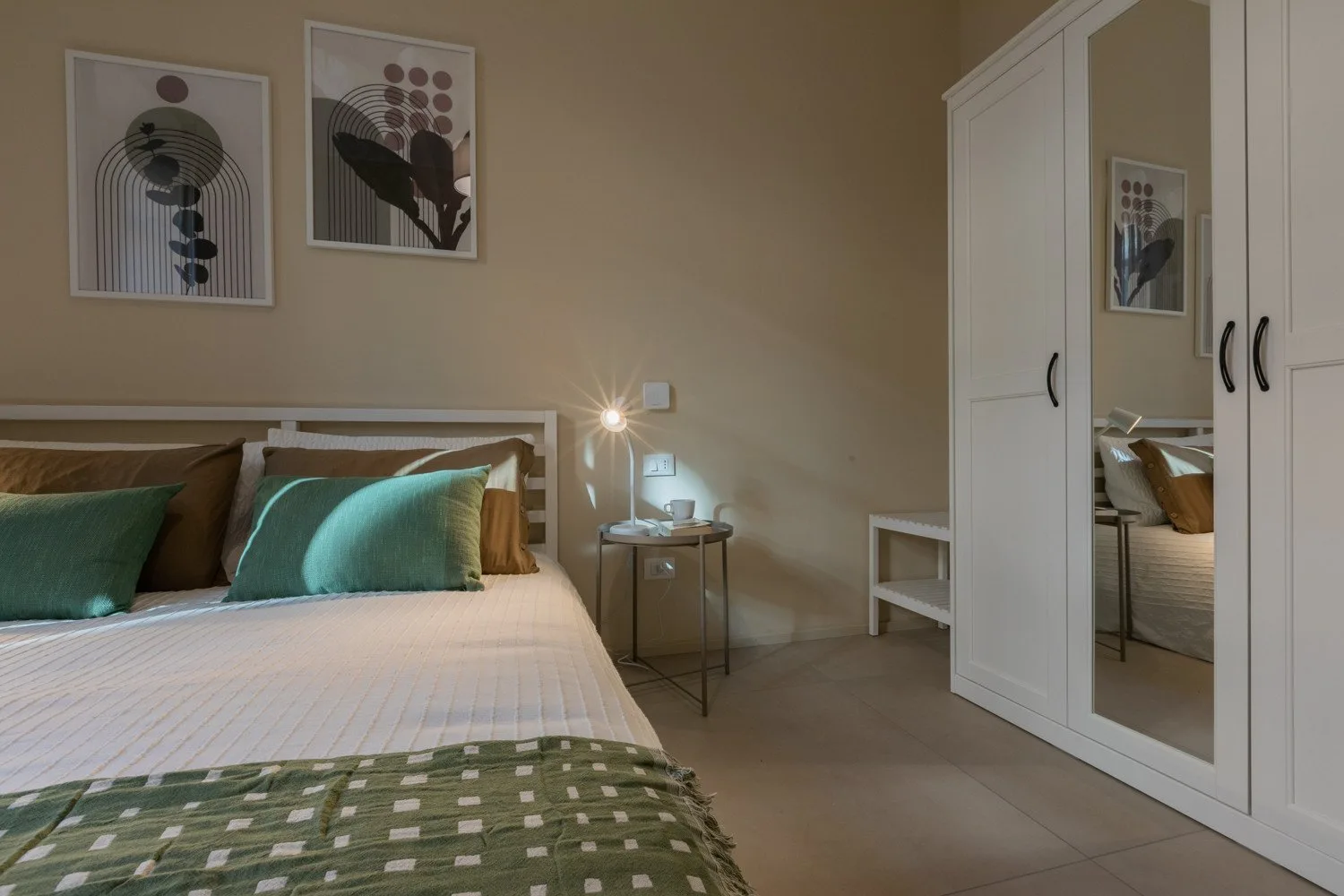 Un dormitorio con cama, mesita de noche y armario con espejo.