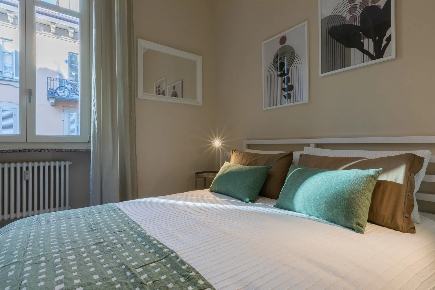 Un dormitorio con una cama bien tendida y cuadros en la pared.