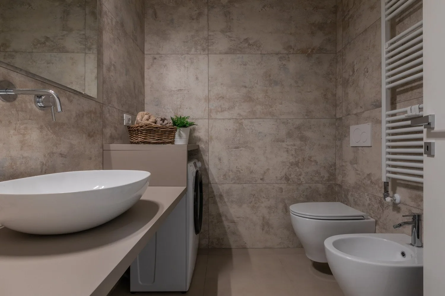 Un baño con azulejos, un lavabo sobre la encimera y un inodoro.