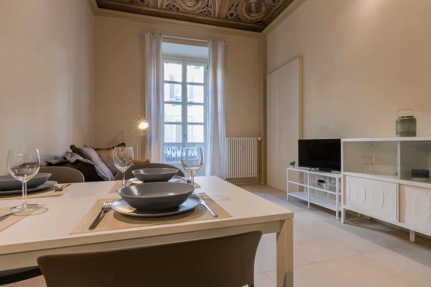 Un comedor con la mesa puesta, asientos y un televisor.
