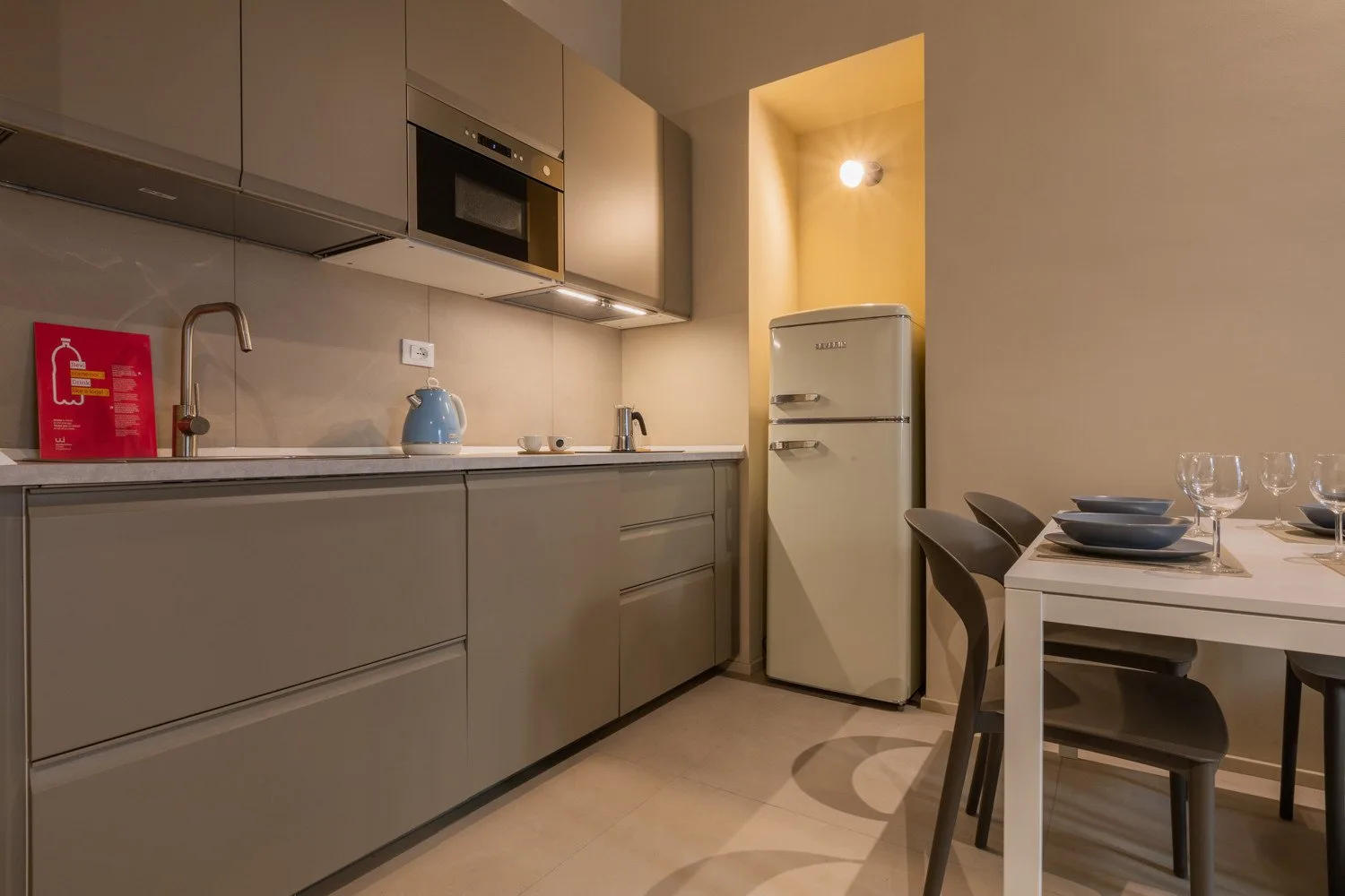 Una cocina moderna con gabinetes grises, un refrigerador y una mesa de comedor.