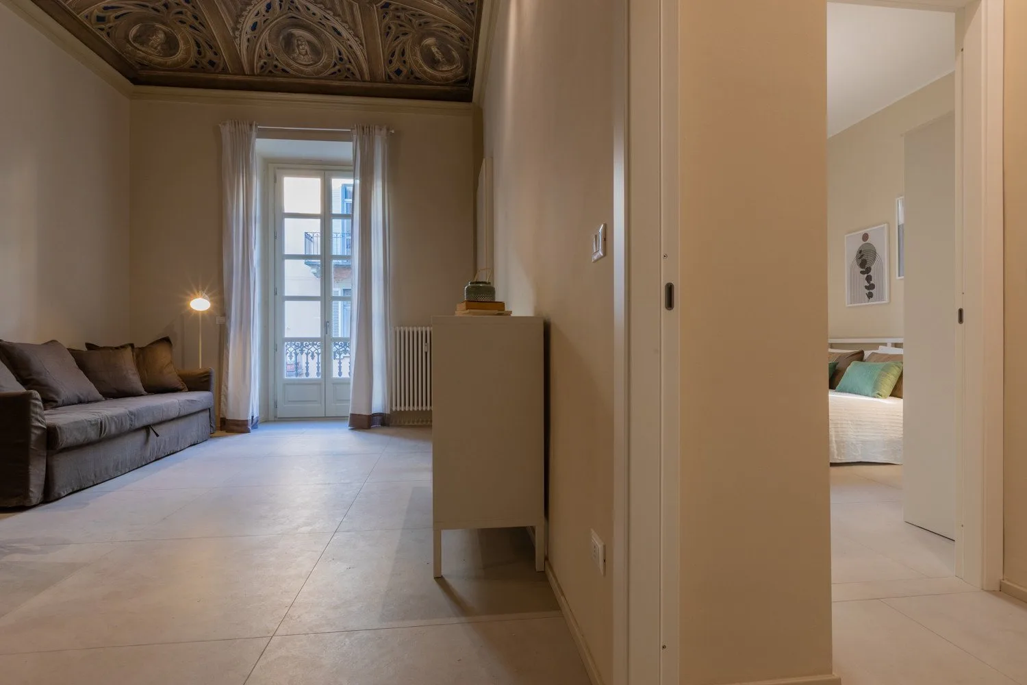 Una sala de estar con asientos y una ventana alta que da a un balcón.