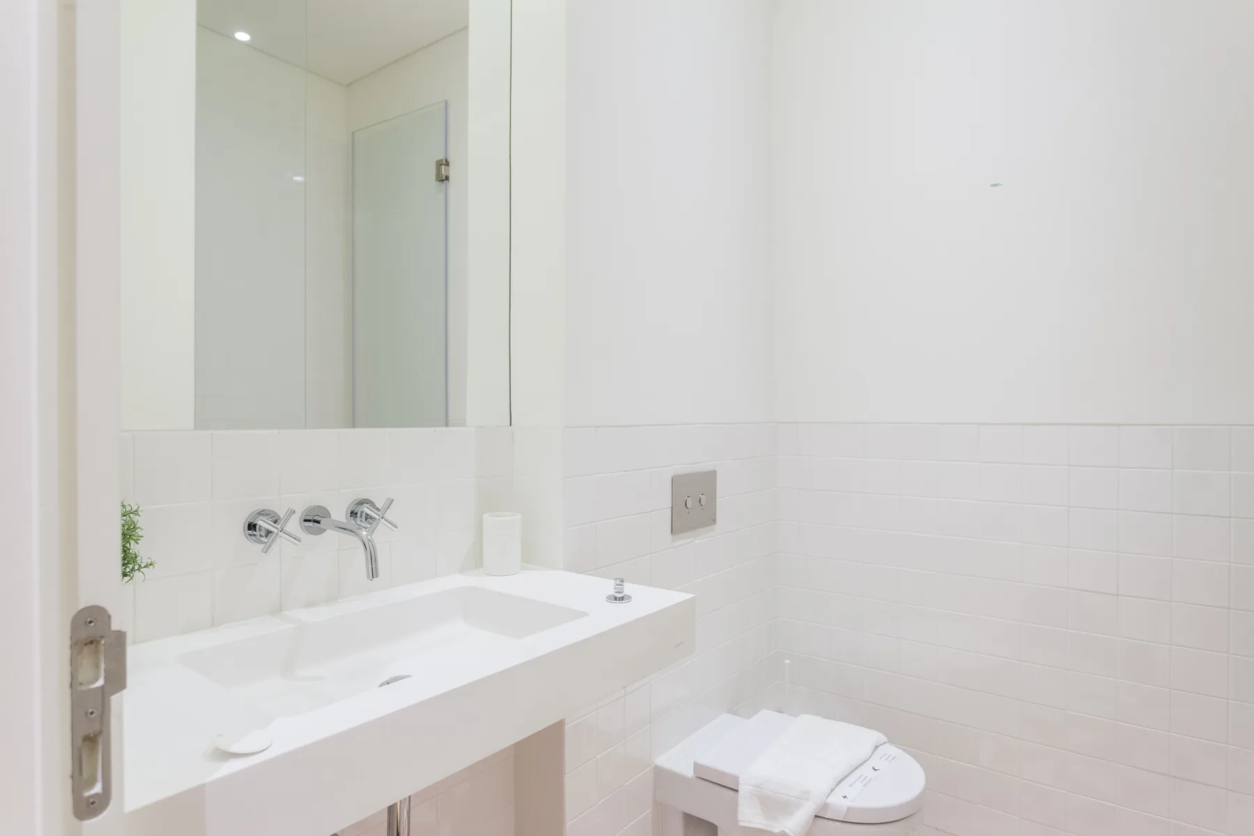 Un baño blanco y luminoso con lavabo, espejo e inodoro.