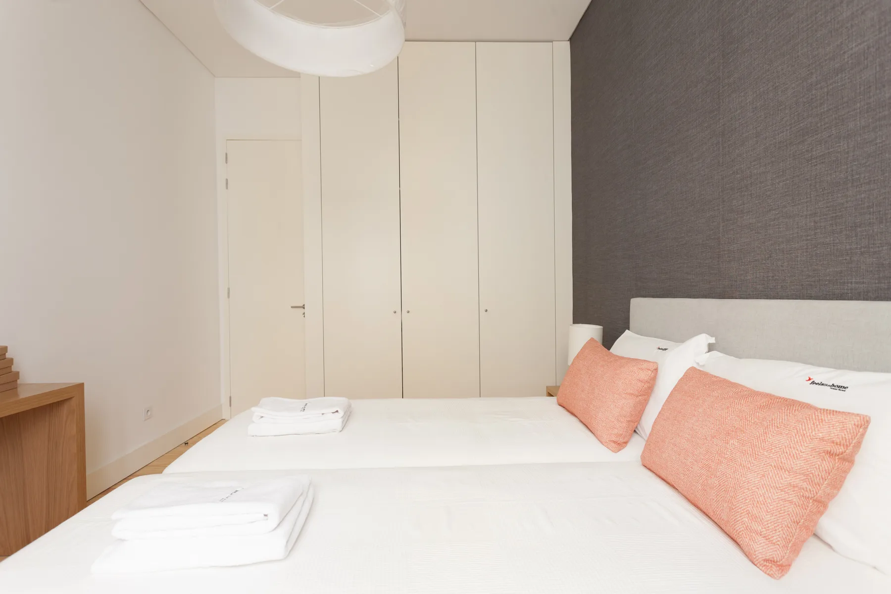 Un dormitorio con una cama bien hecha y cojines de color coral.