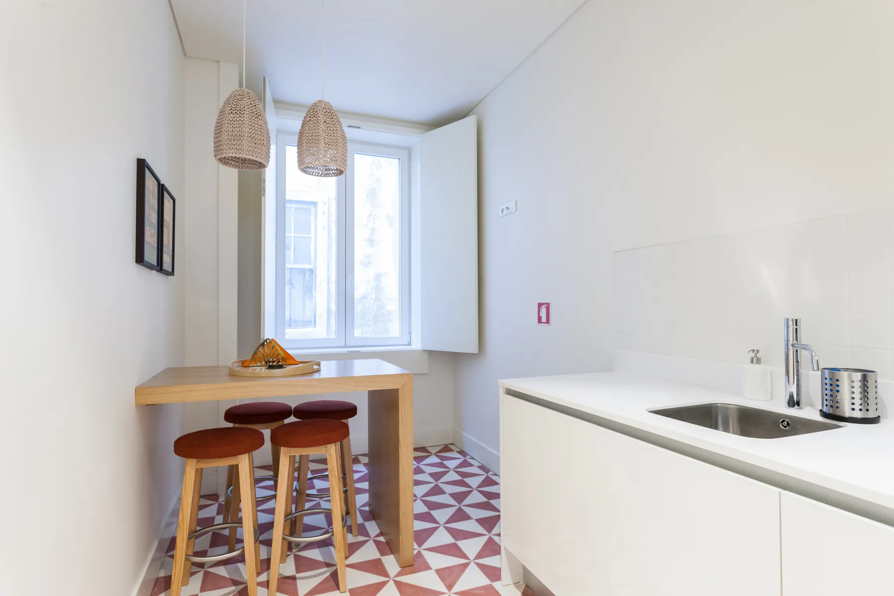 A bright kitchen with a wooden counter, sink, and patterned tile floor.