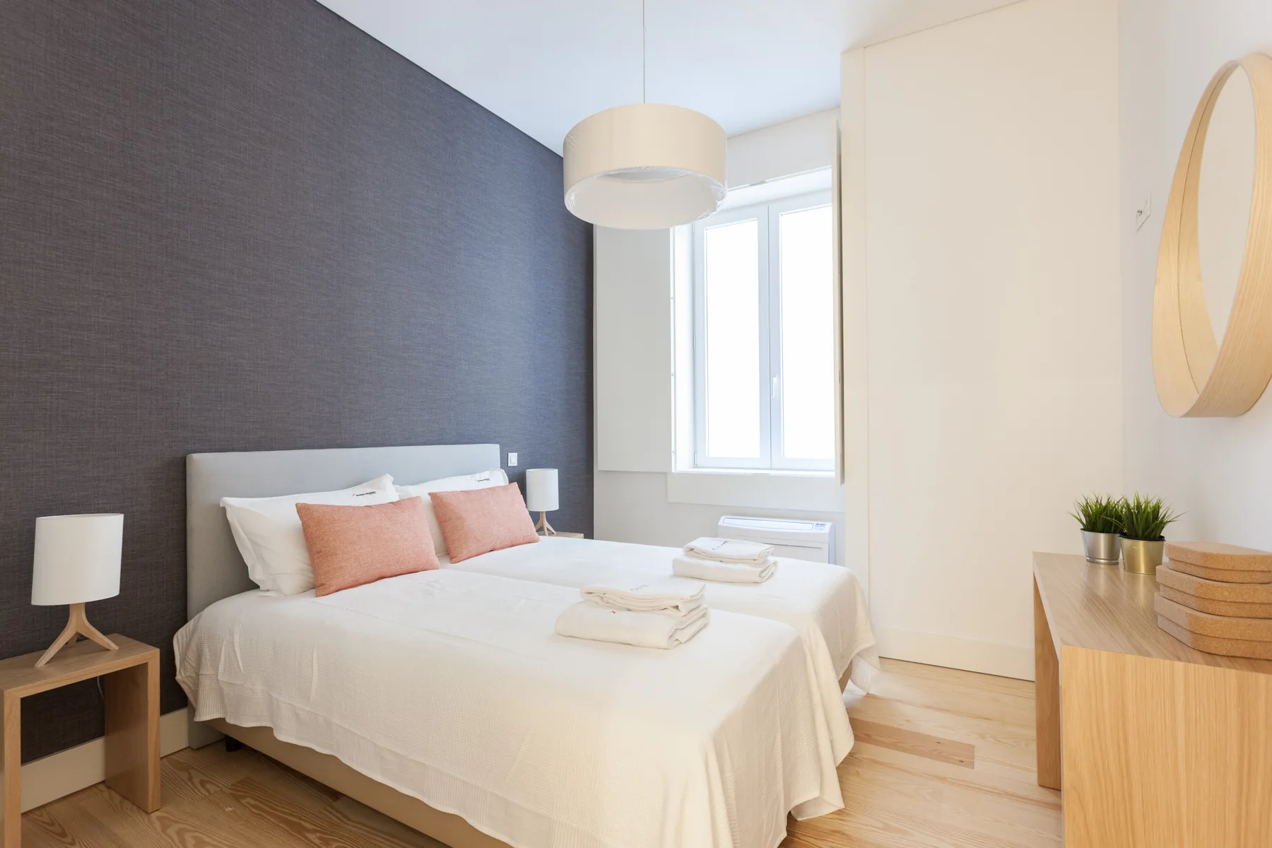 A bright bedroom with a neatly made bed and a large window.