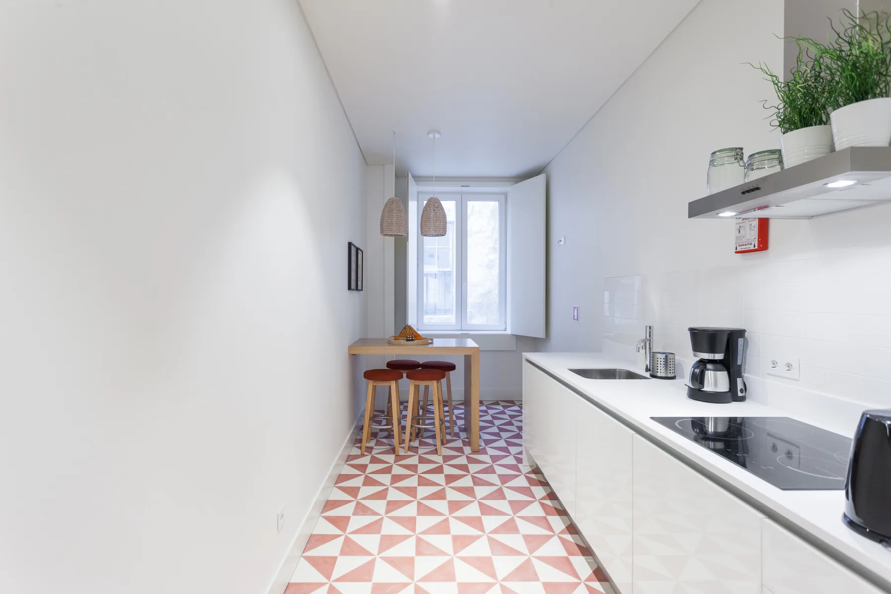 Una cocina luminosa con una encimera larga y una pequeña mesa junto a la ventana.