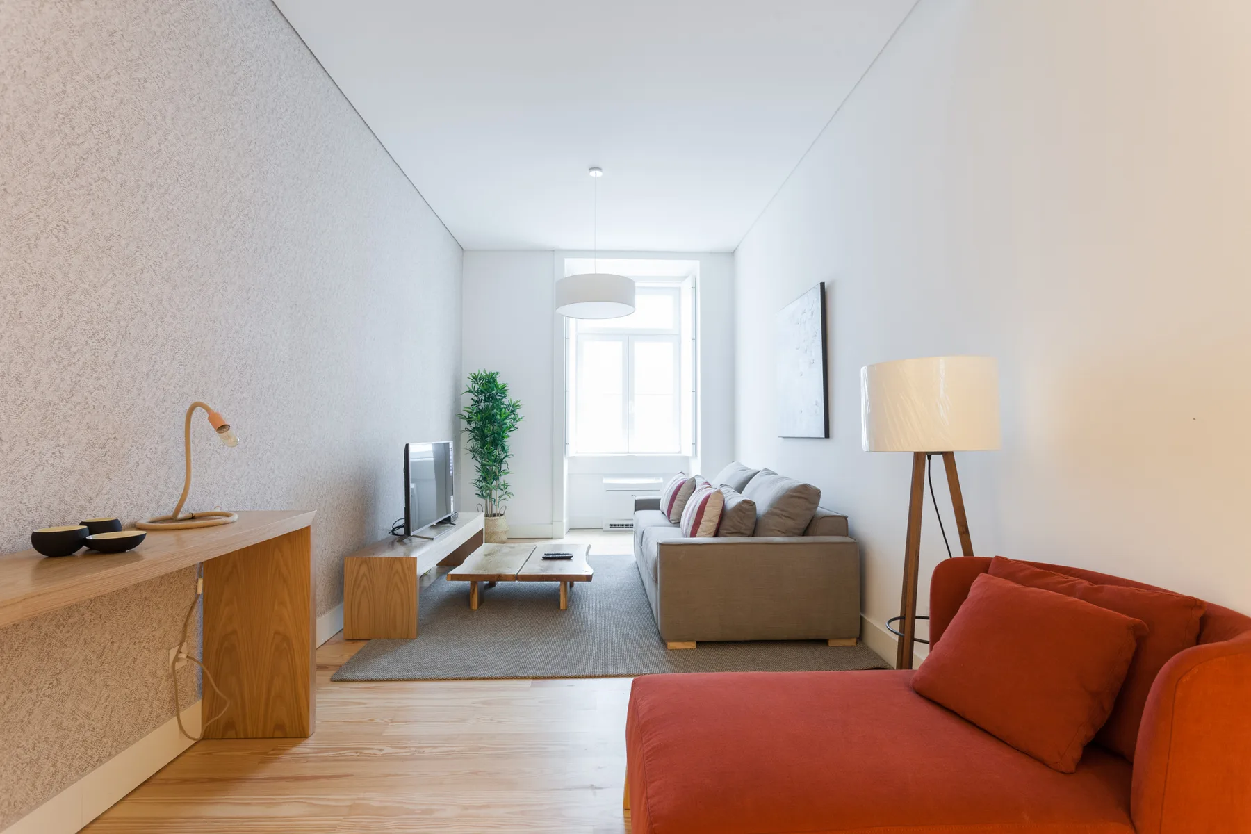 Luminoso salón con asientos, un televisor y una mesa de centro.