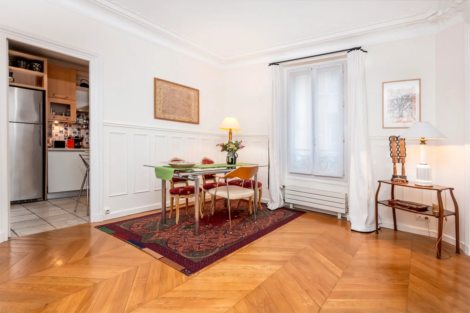 A bright dining area with a table and chairs on a patterned rug.