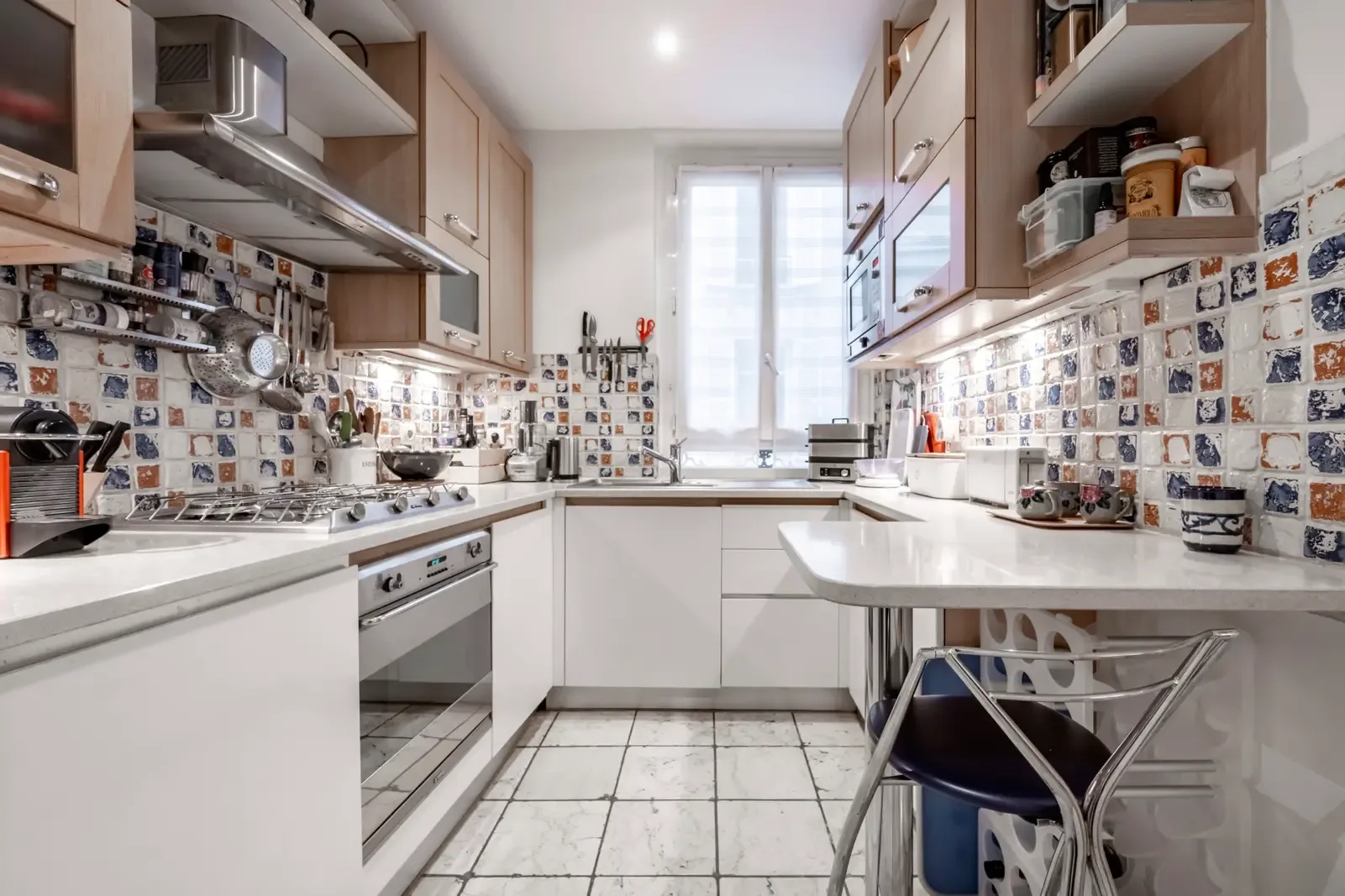 A bright kitchen with counters, cabinets, and a window at the far end.