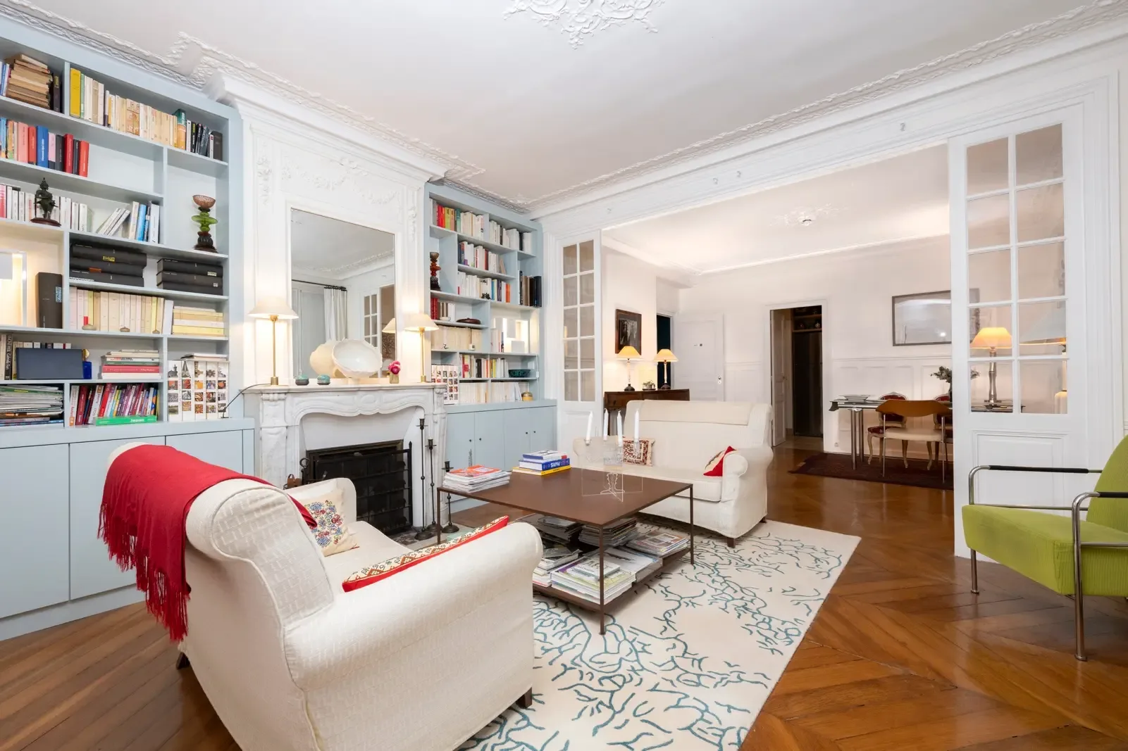 A bright living room with seating, bookshelves, and a fireplace.