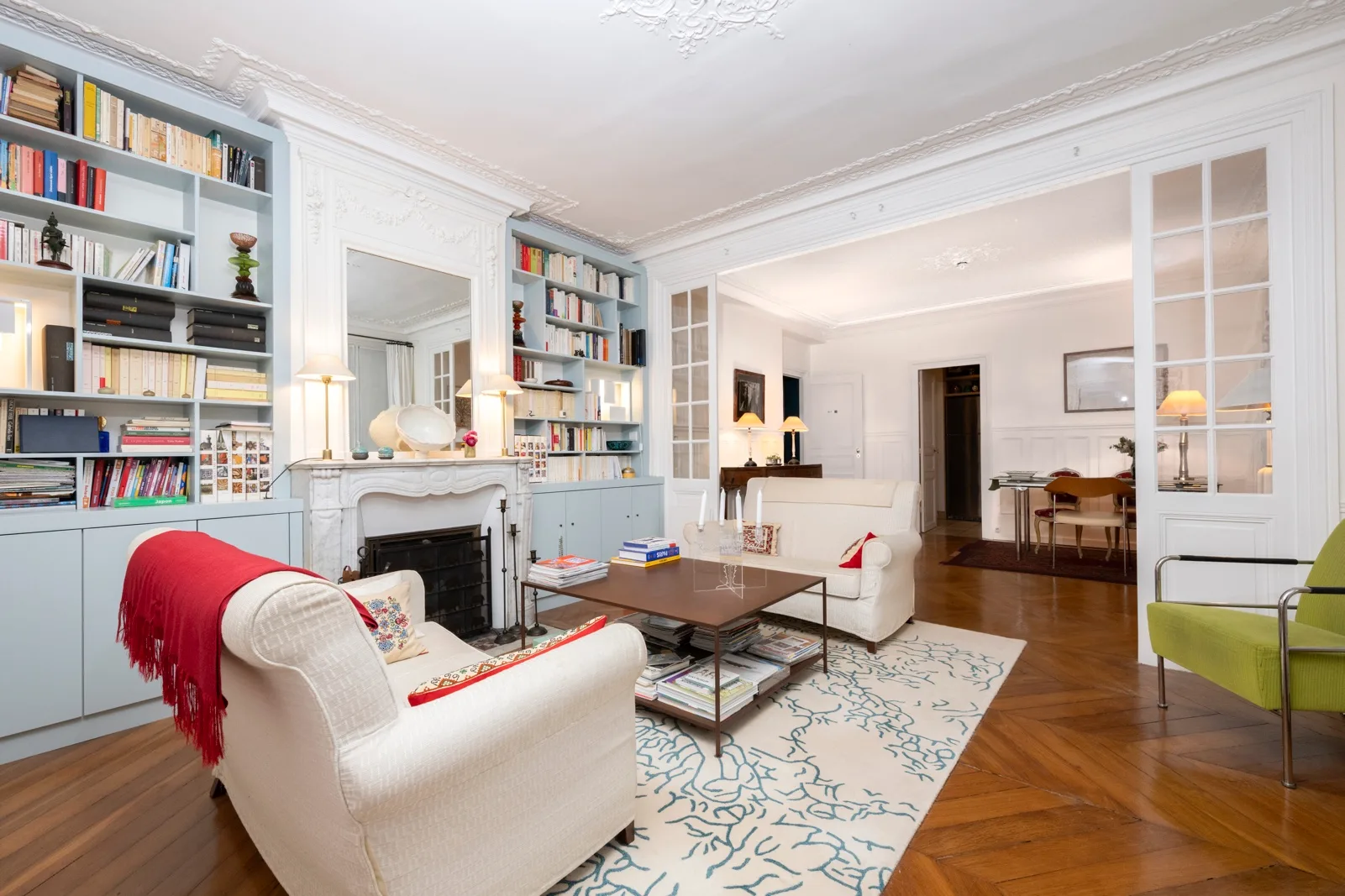 A bright living room with built-in bookshelves, seating, and a dining area.