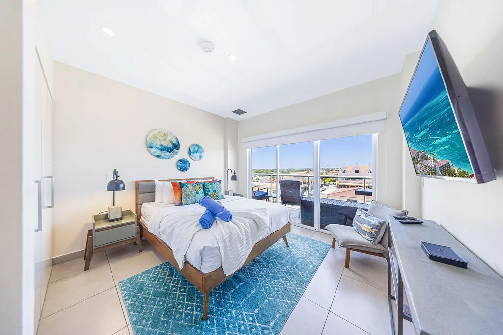 Step into your serene coastal-inspired bedroom, where ocean-blue accents and crisp white linens invite you to unwind. Enjoy your private balcony and modern TV for ultimate relaxation.