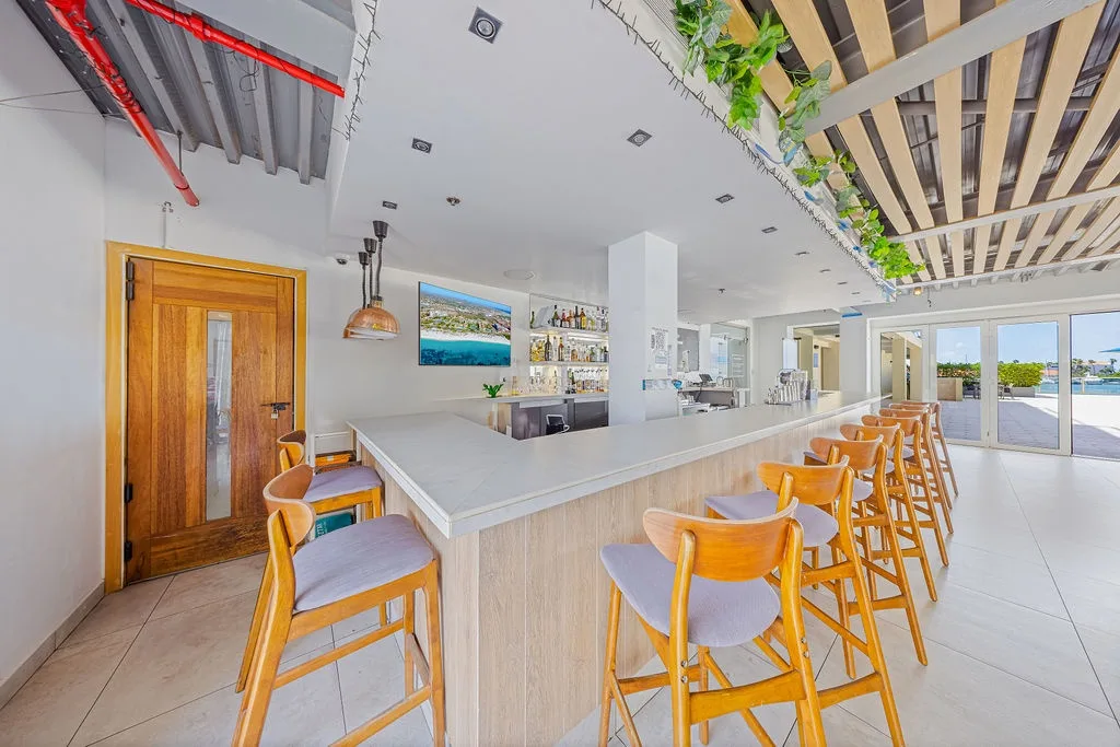 Pull up a seat at the stylish bar and enjoy crafted cocktails in this bright, modern lounge space featuring hanging greenery and a sleek marble countertop that invites you to unwind.