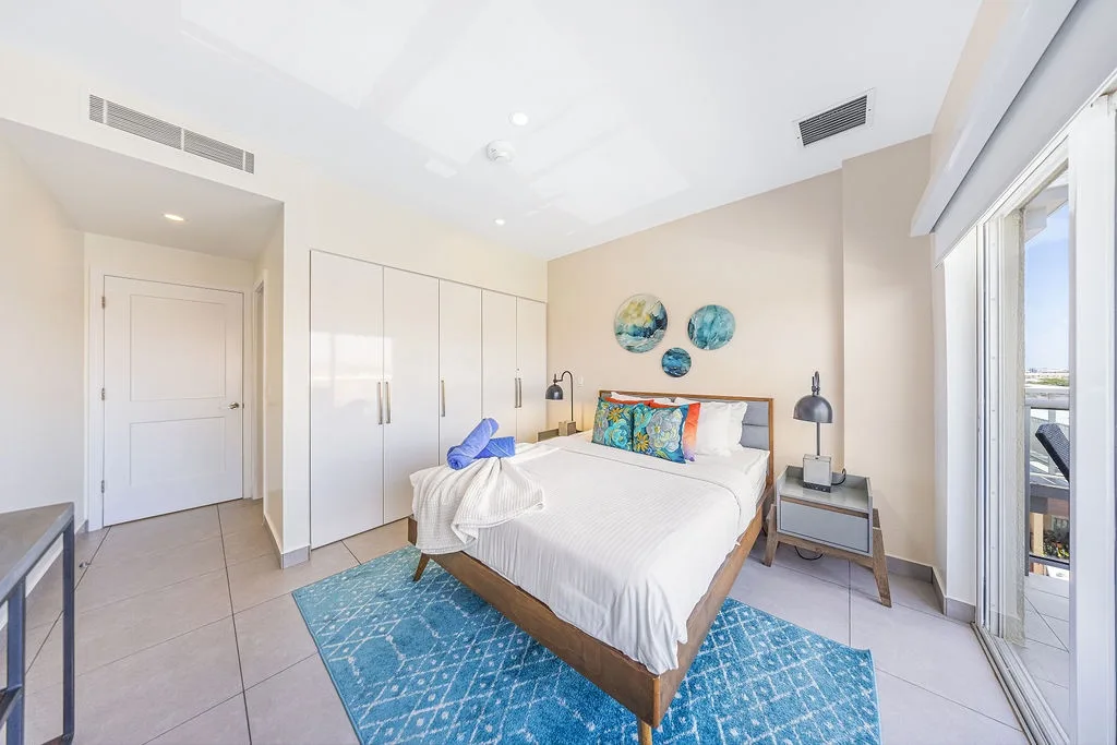 Sink into crisp white linens and coastal vibes. Your tranquil bedroom features elegant storage, modern decor, and opens to your private balcony retreat.