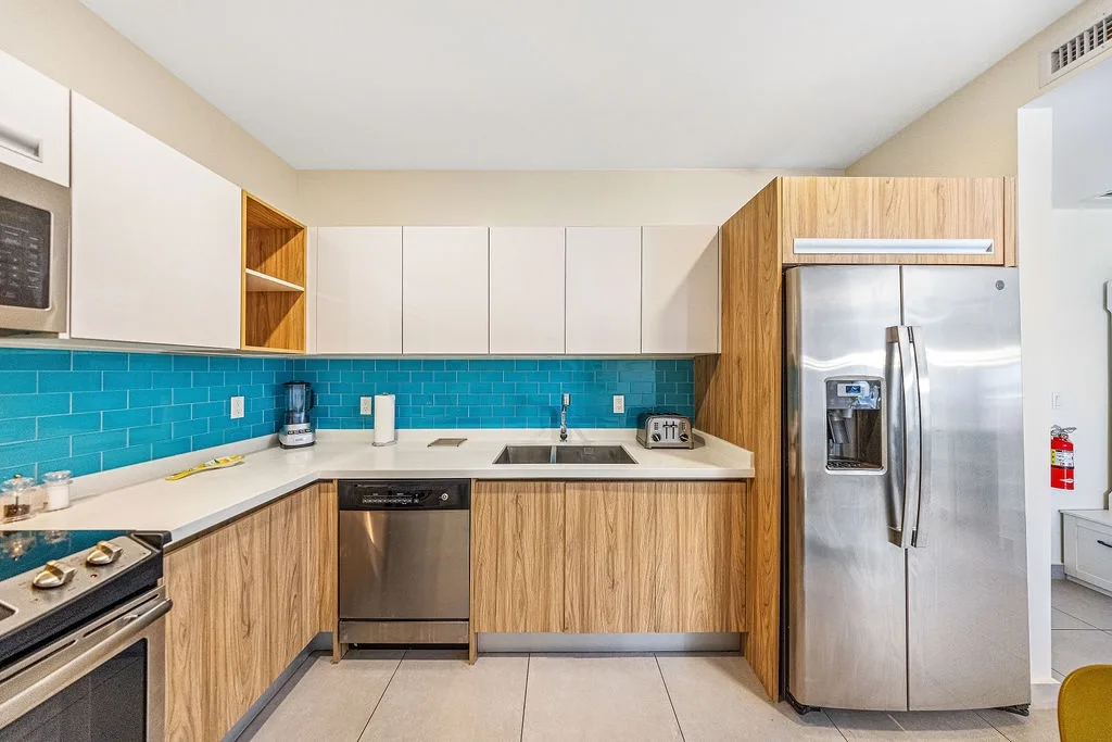 You'll love preparing meals in this bright, modern kitchen with its vibrant turquoise backsplash and sleek stainless appliances—everything you need to cook up vacation memories.