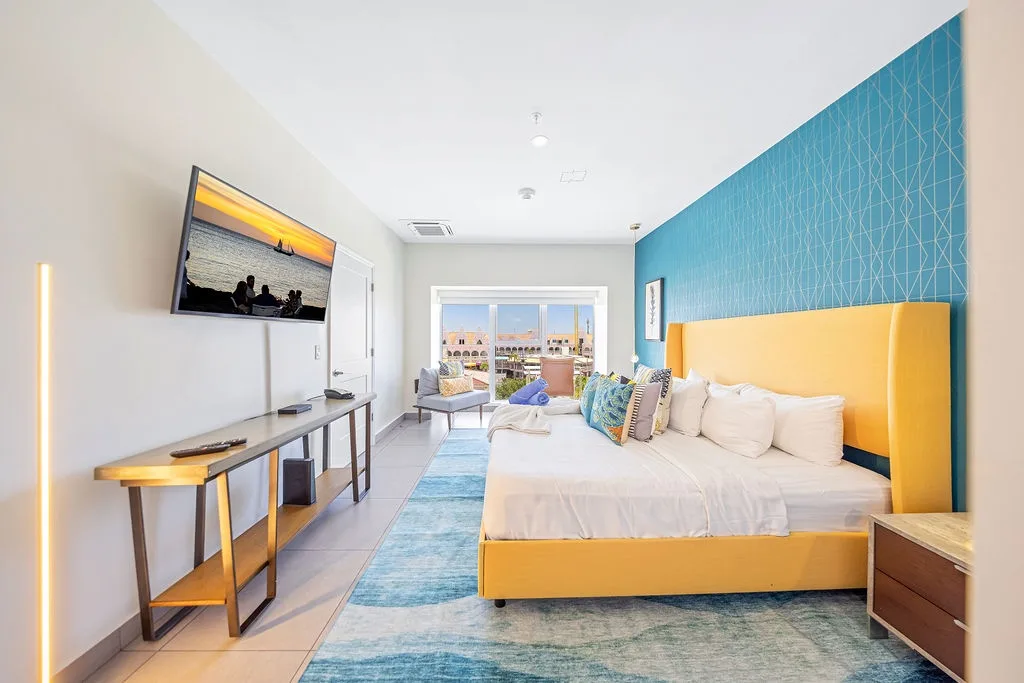 Wake up to rooftop views in your sun-drenched bedroom, where golden tones blend with ocean-blue accents. Relax on plush bedding, enjoy entertainment on the flat-screen, and unwind in your private, modern sanctuary.
