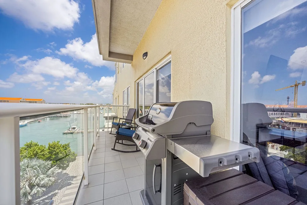 This waterfront balcony offers a spacious outdoor haven with a built-in BBQ, perfect for grilling while taking in stunning marina and sky views.