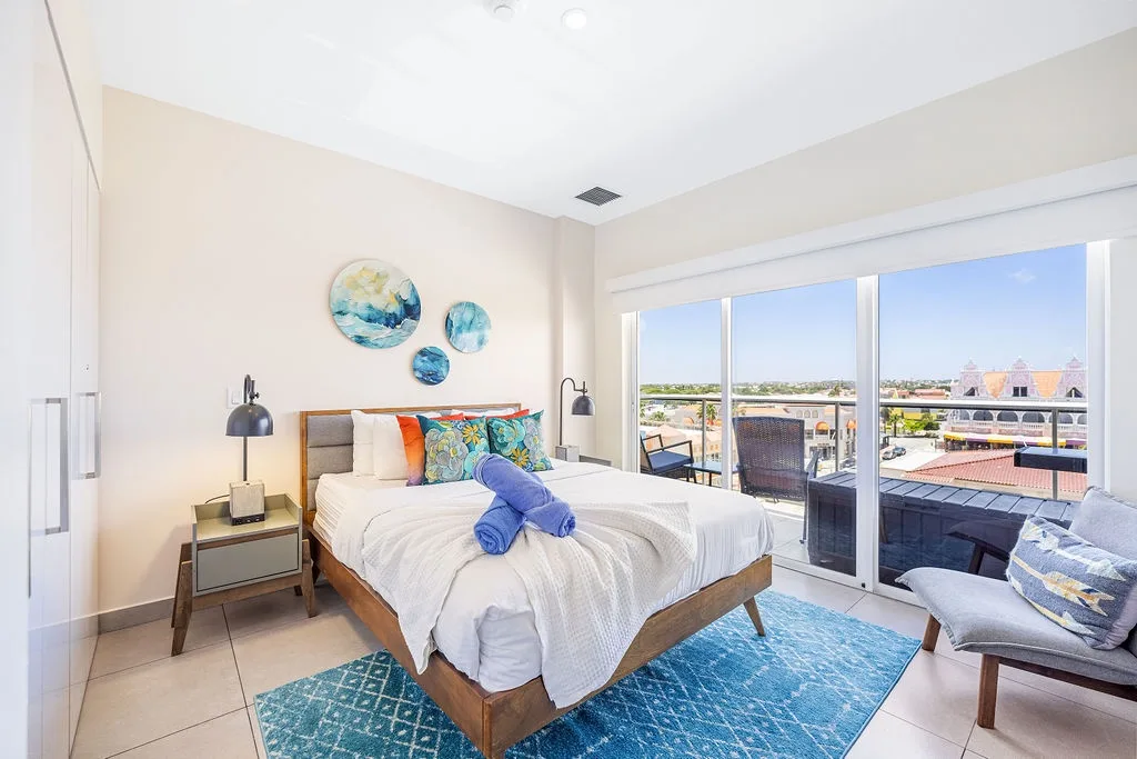 Wake up to city views from your comfortable bed and step onto your private balcony for morning sunshine. Clean, coastal decor and thoughtful touches make this bright bedroom a perfect retreat.