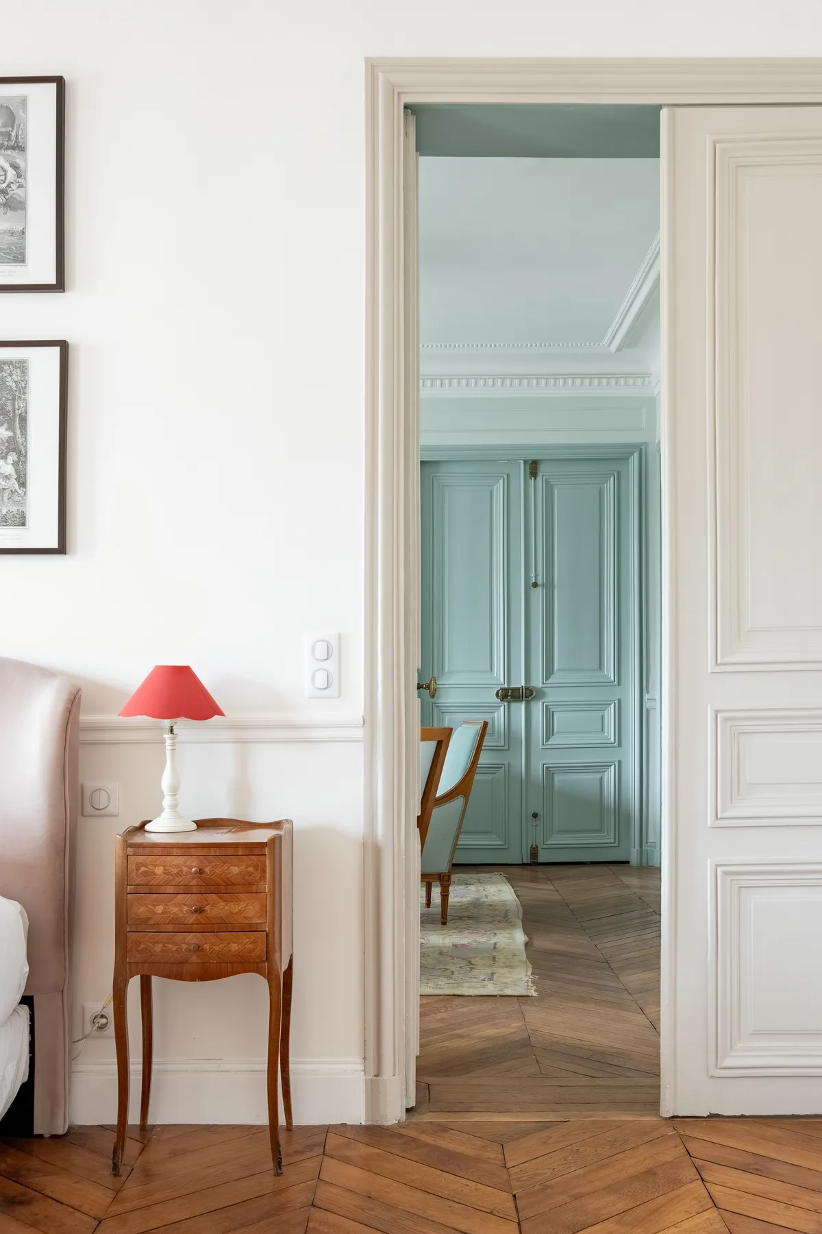 A sitting room opens through a doorway to a blue paneled room.