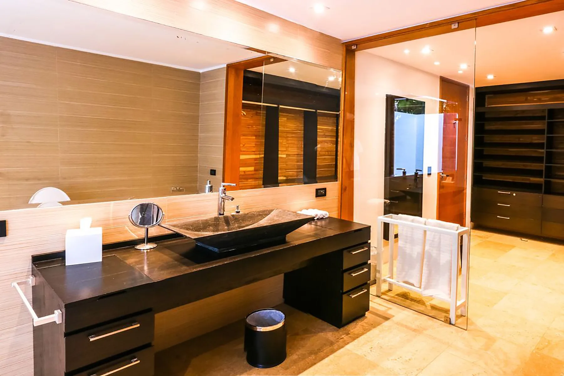 Un baño moderno cuenta con un largo lavabo, un lavamanos sobre encimera y un espejo grande.