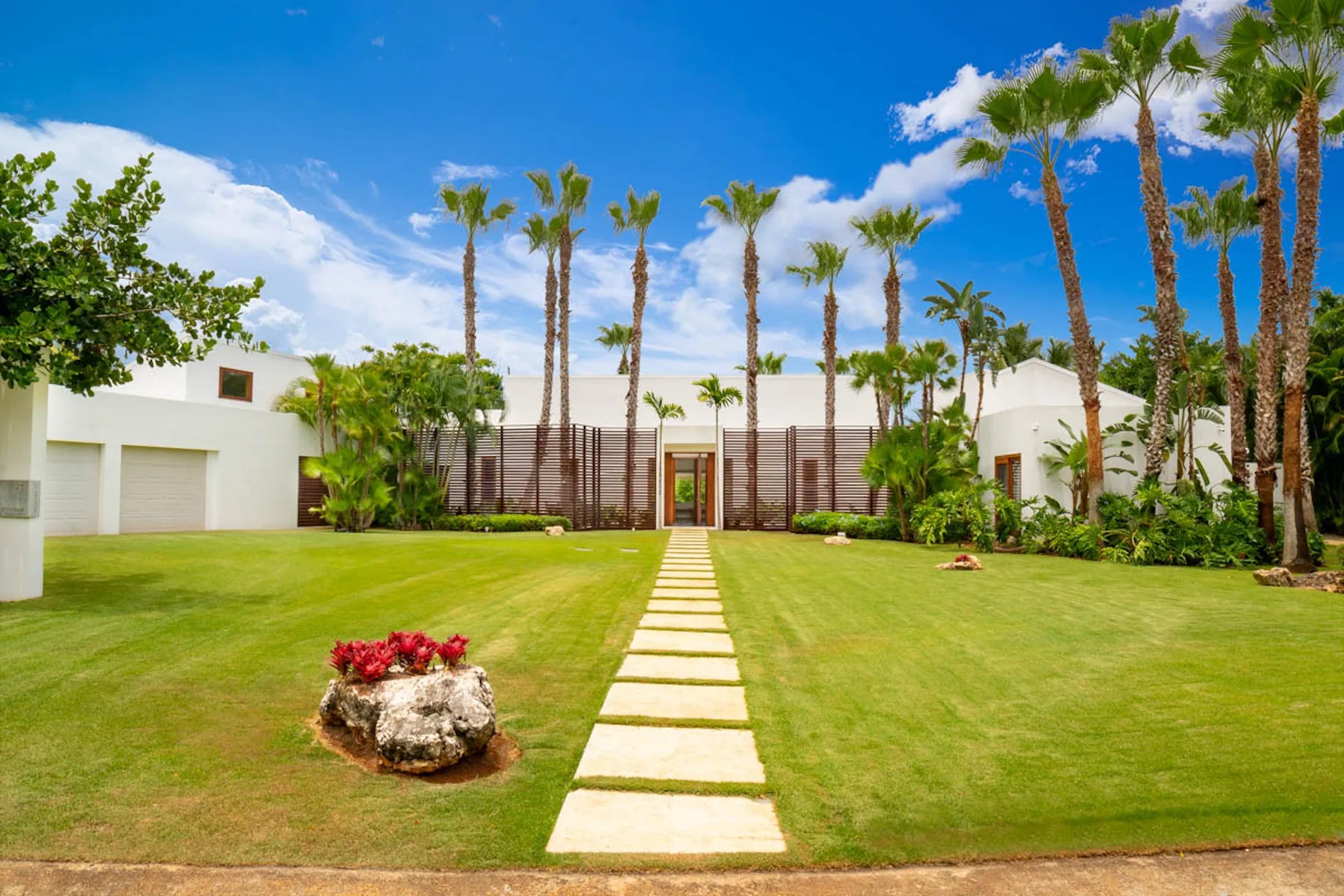 Una propiedad residencial ajardinada con un sendero de piedra que conduce a un edificio blanco moderno.