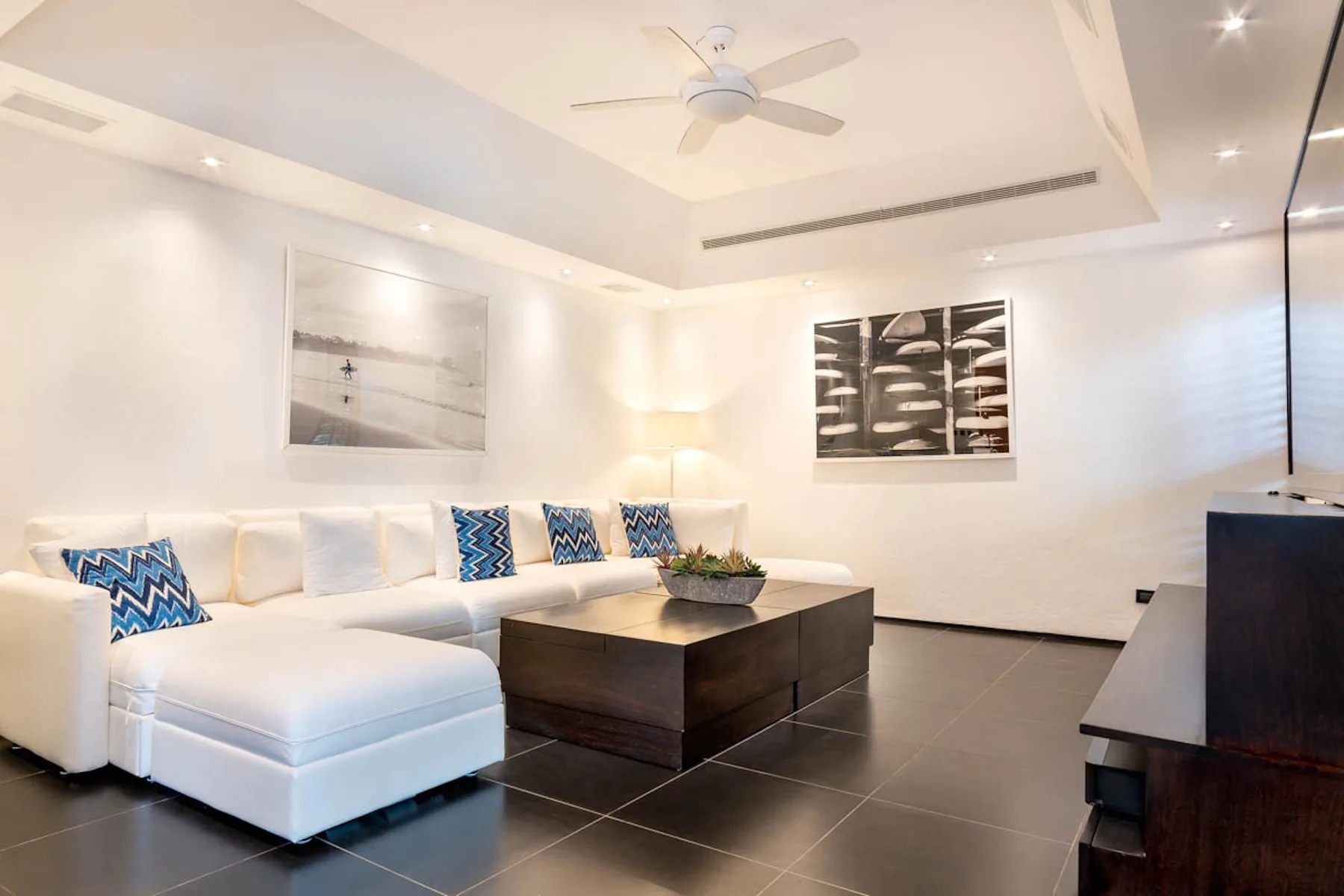 Una sala luminosa con asientos blancos y una mesa de centro oscura.