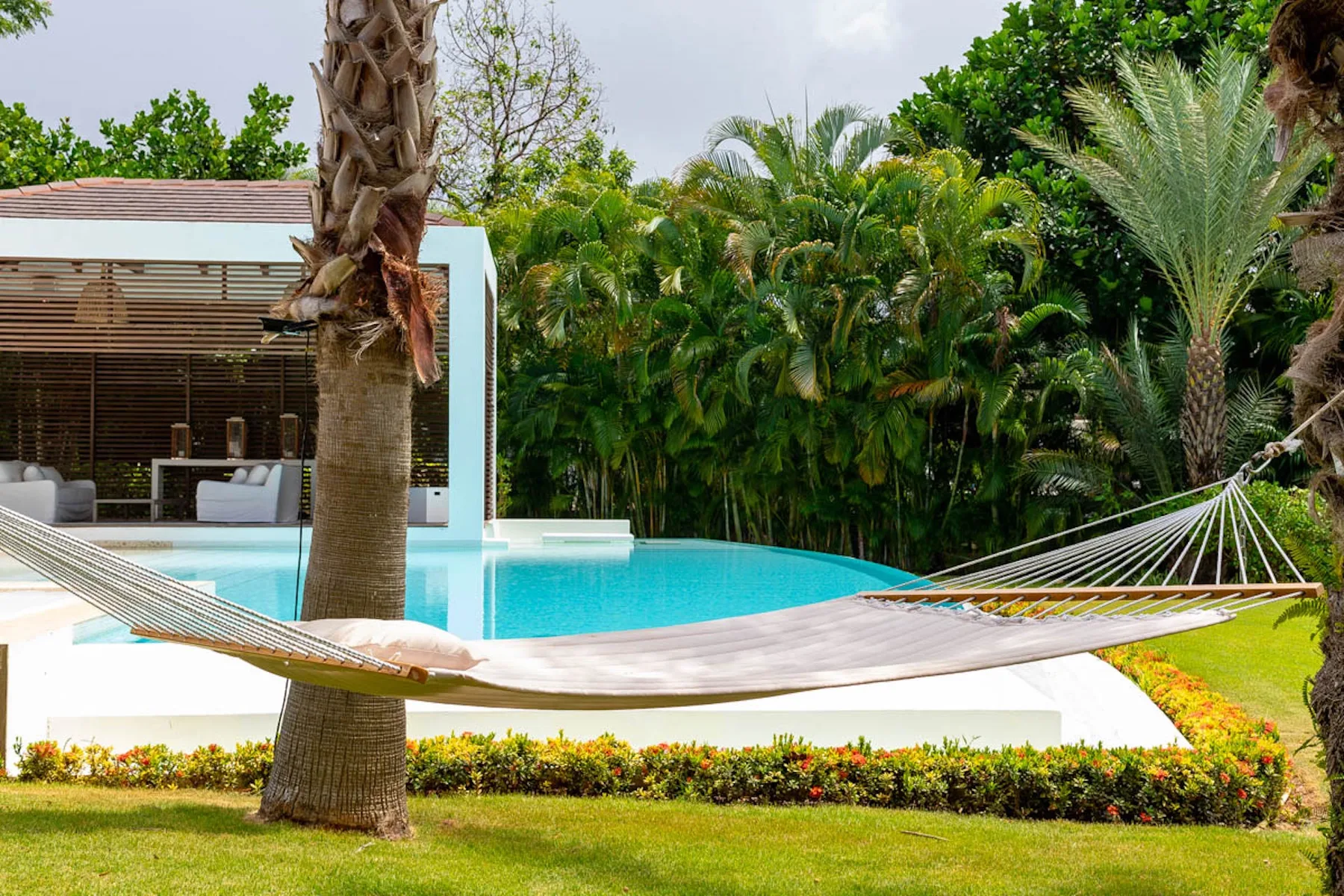 Una piscina al aire libre junto a un patio sombreado, con hamacas en primer plano.