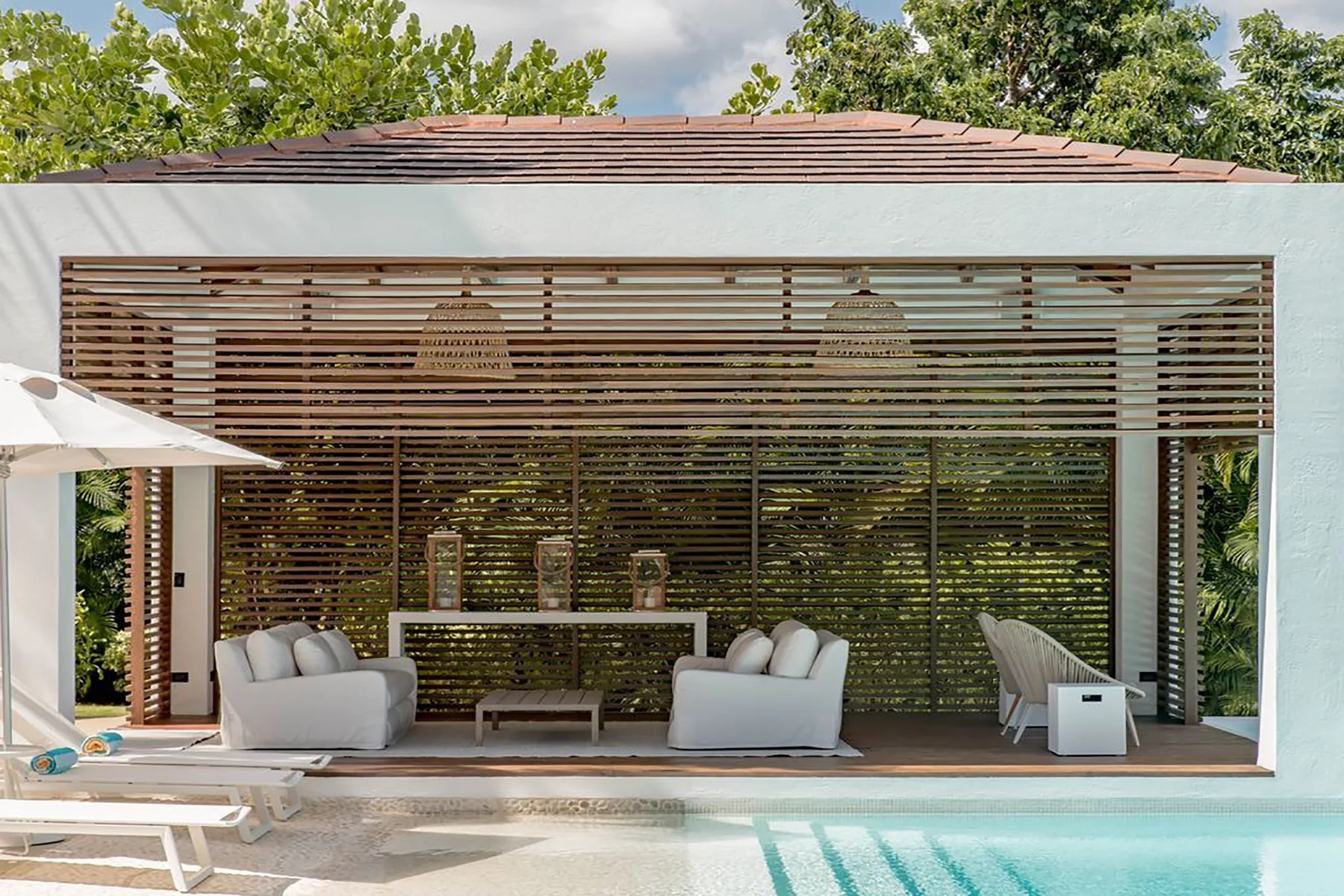 Una sala exterior cubierta con asientos se abre a una piscina.