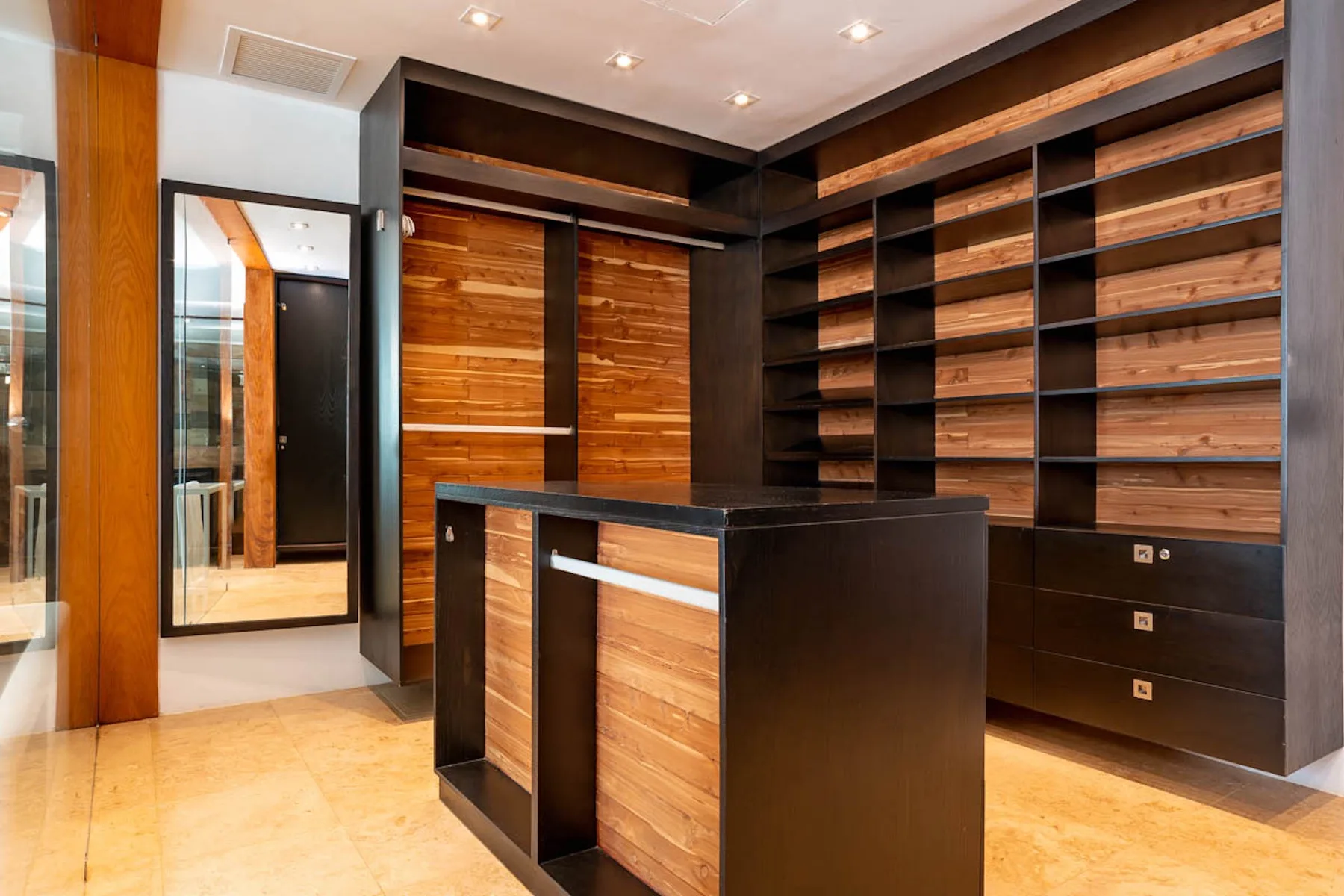 Un vestidor con estantes de madera y una isla central.