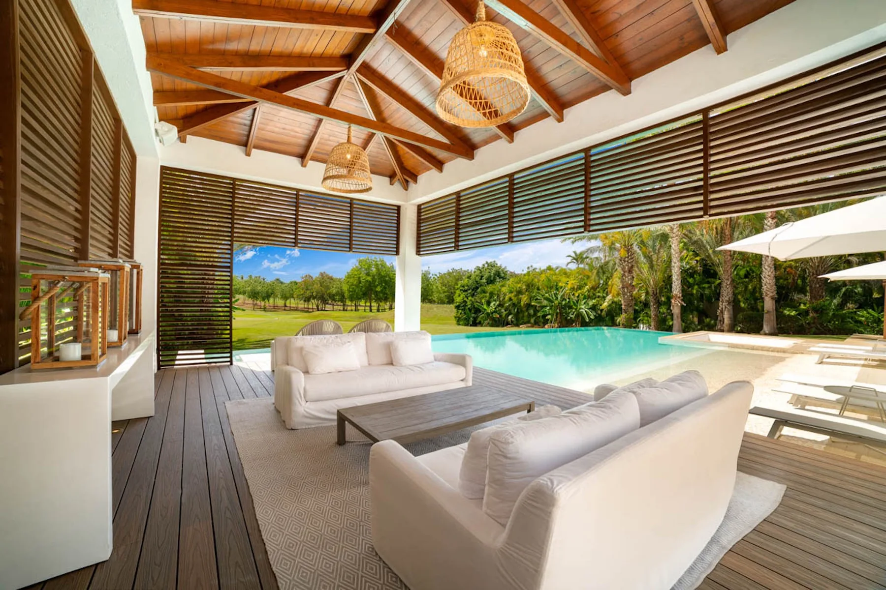 Una sala al aire libre con asientos blancos da a una piscina.