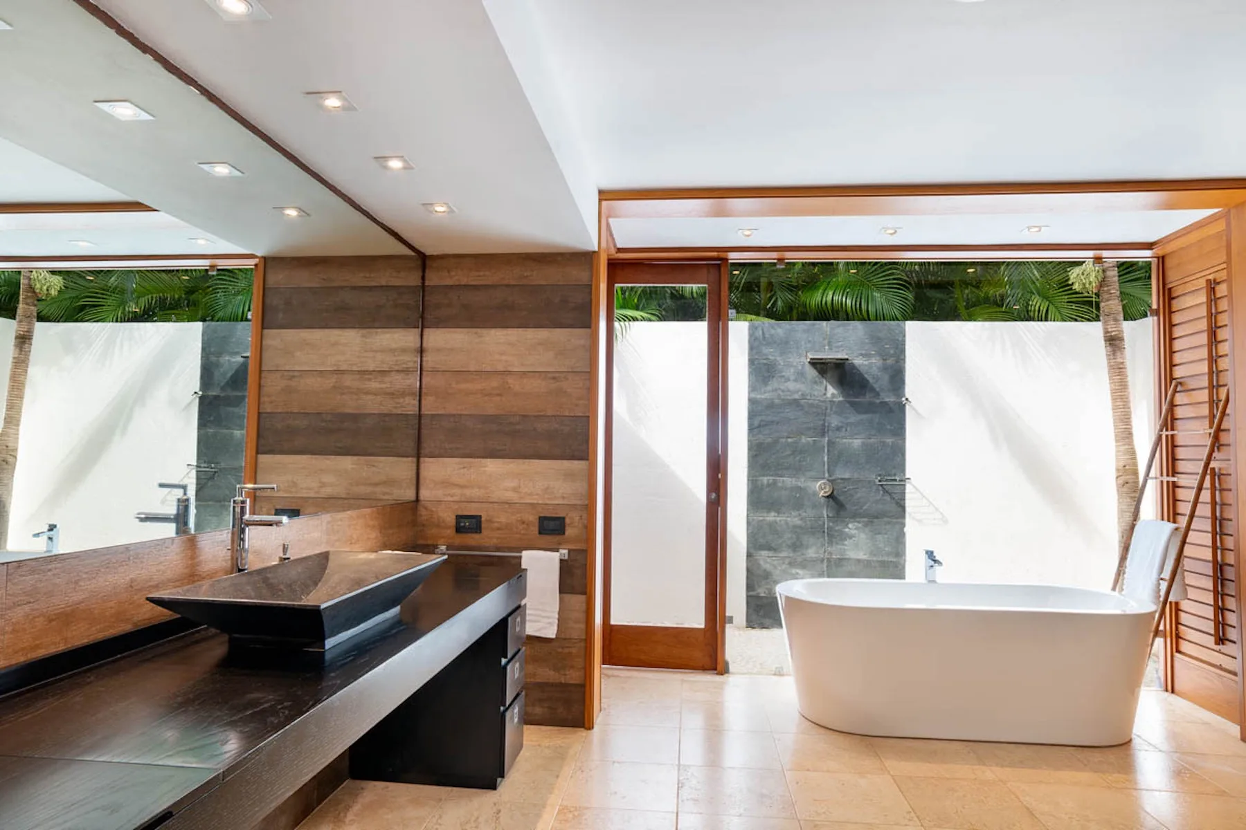 Un baño moderno con una bañera exenta y un lavabo oscuro.