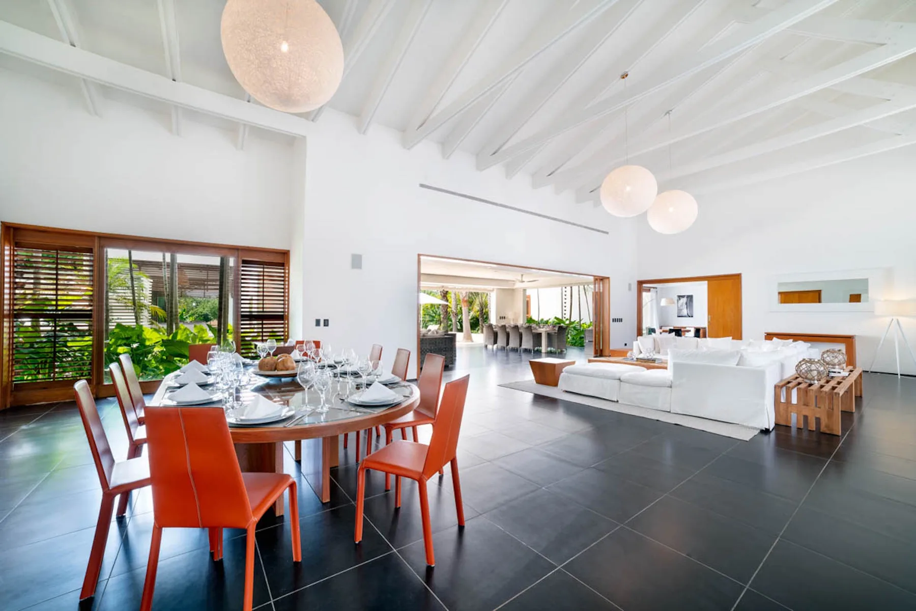 Un luminoso espacio abierto de comedor y sala de estar, con una mesa puesta y asientos blancos.
