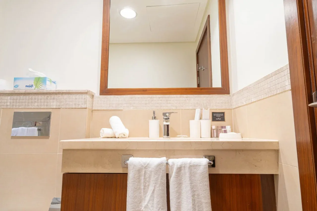 Un lavabo de baño con un espejo amplio y toallas colgadas bajo la encimera.