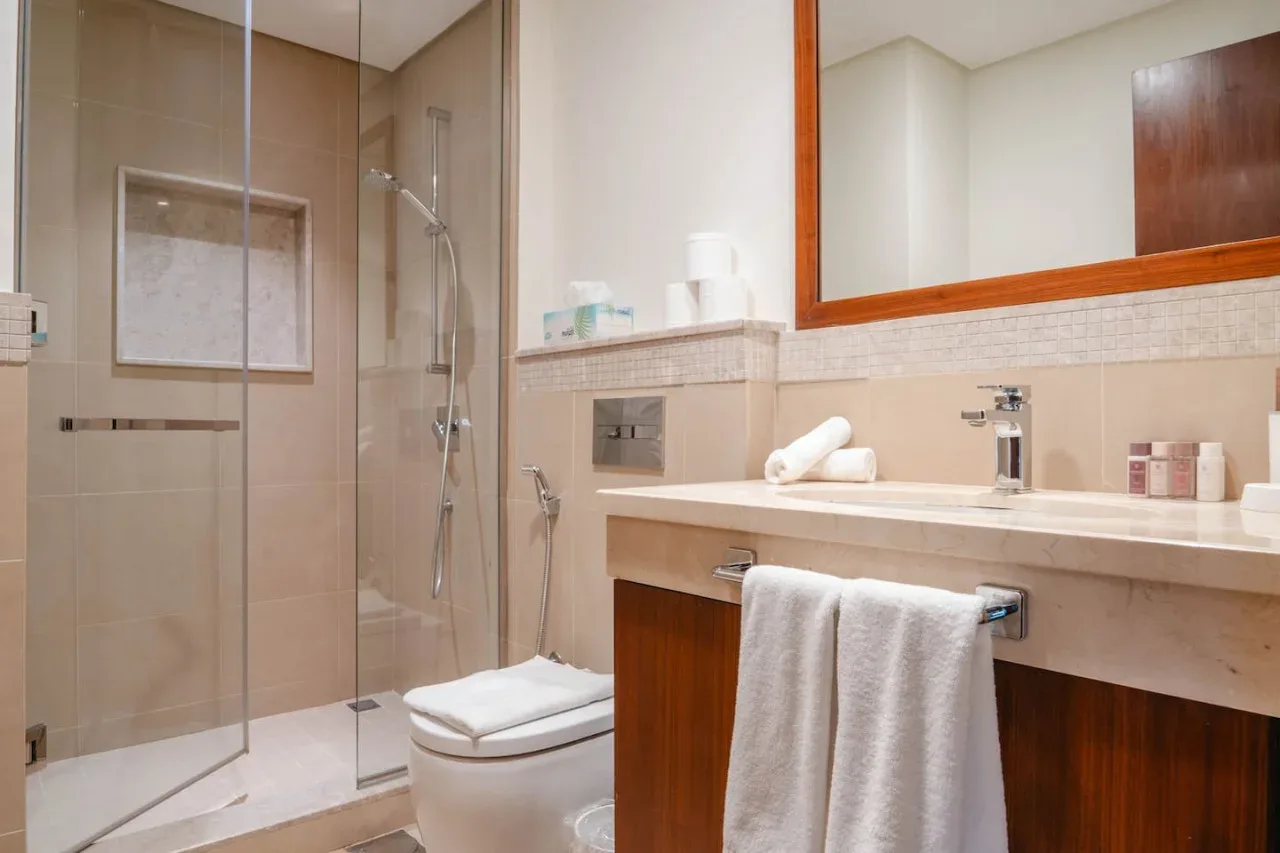 Un baño con ducha de vidrio, inodoro y lavabo con toallas.