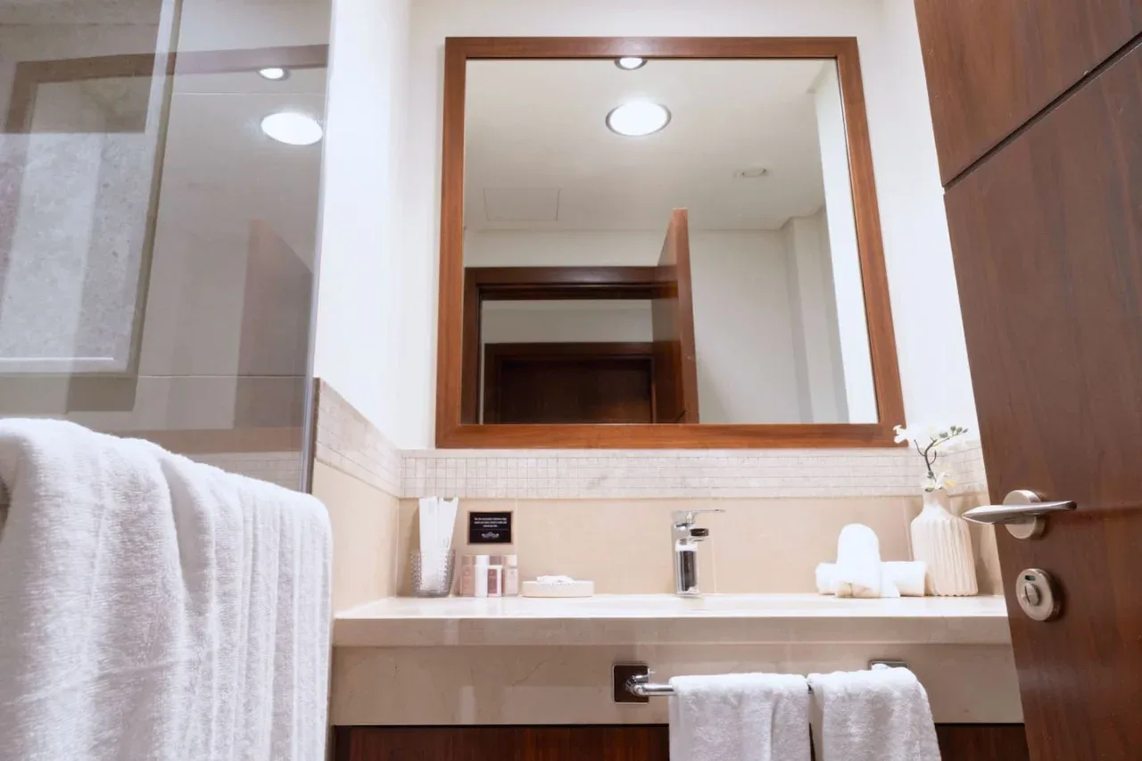 Un lavabo de baño con un espejo grande, un lavamanos y toallas.