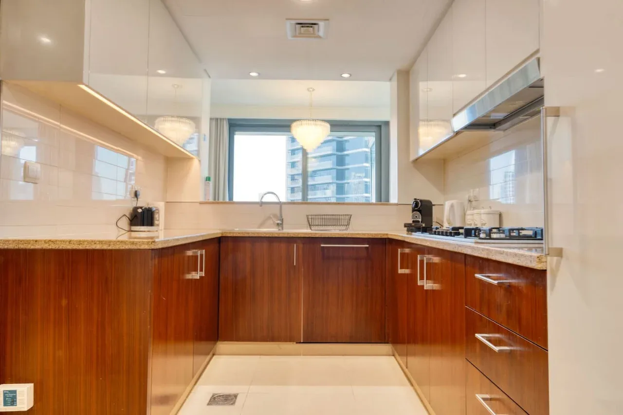 Una cocina moderna con gabinetes de madera oscura, encimeras claras y una ventana central.
