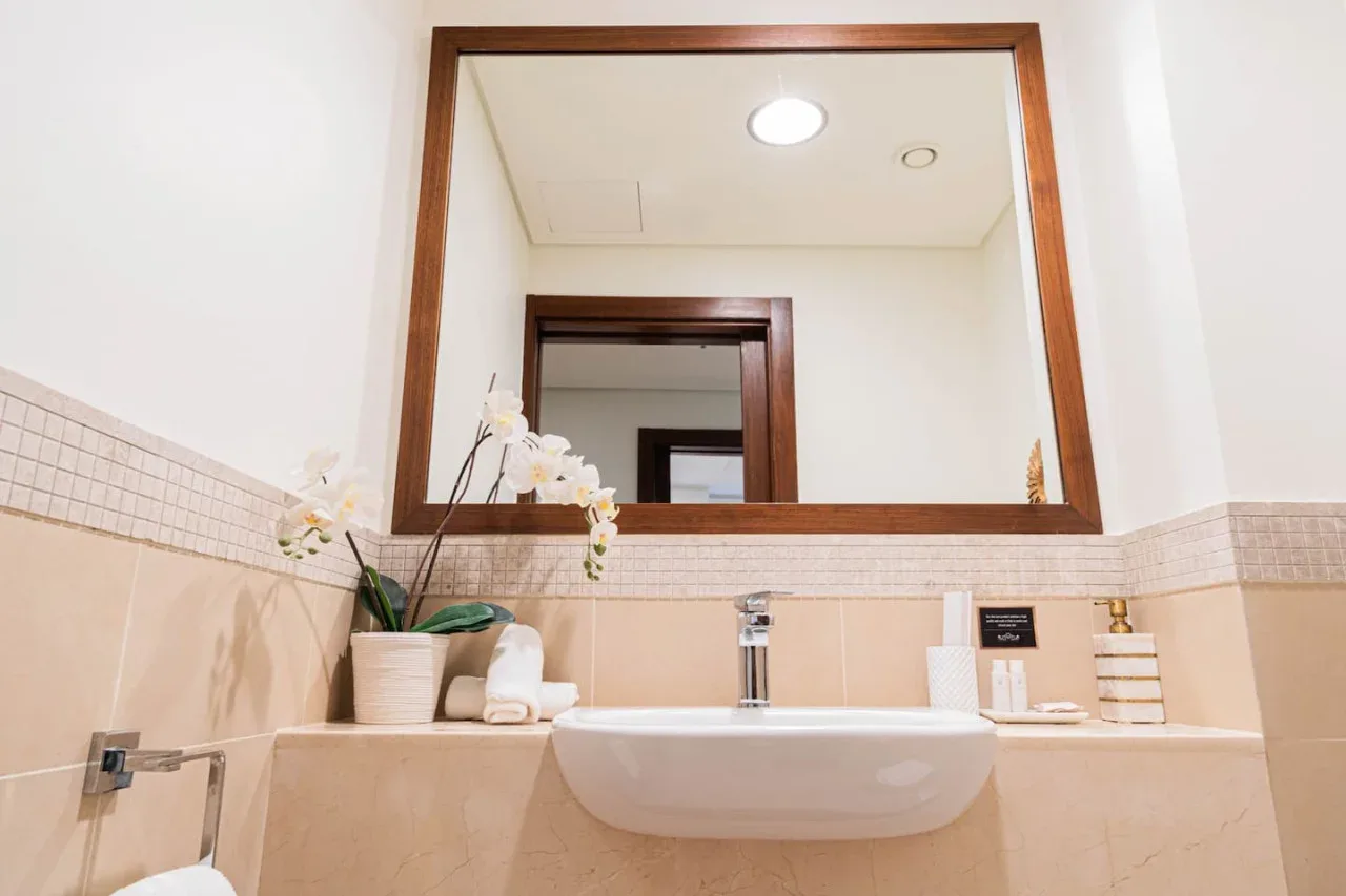 Un lavabo de baño con espejo grande y flores.