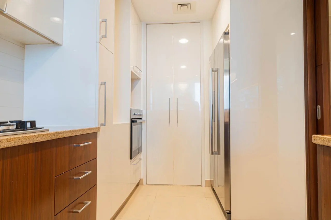 Una cocina moderna y estrecha con gabinetes de madera y electrodomésticos integrados.